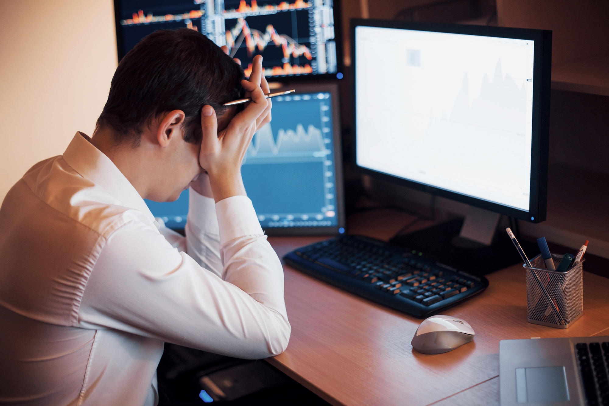 Stressful day at the office. Young businessman holding hands on his face while sitting at the desk