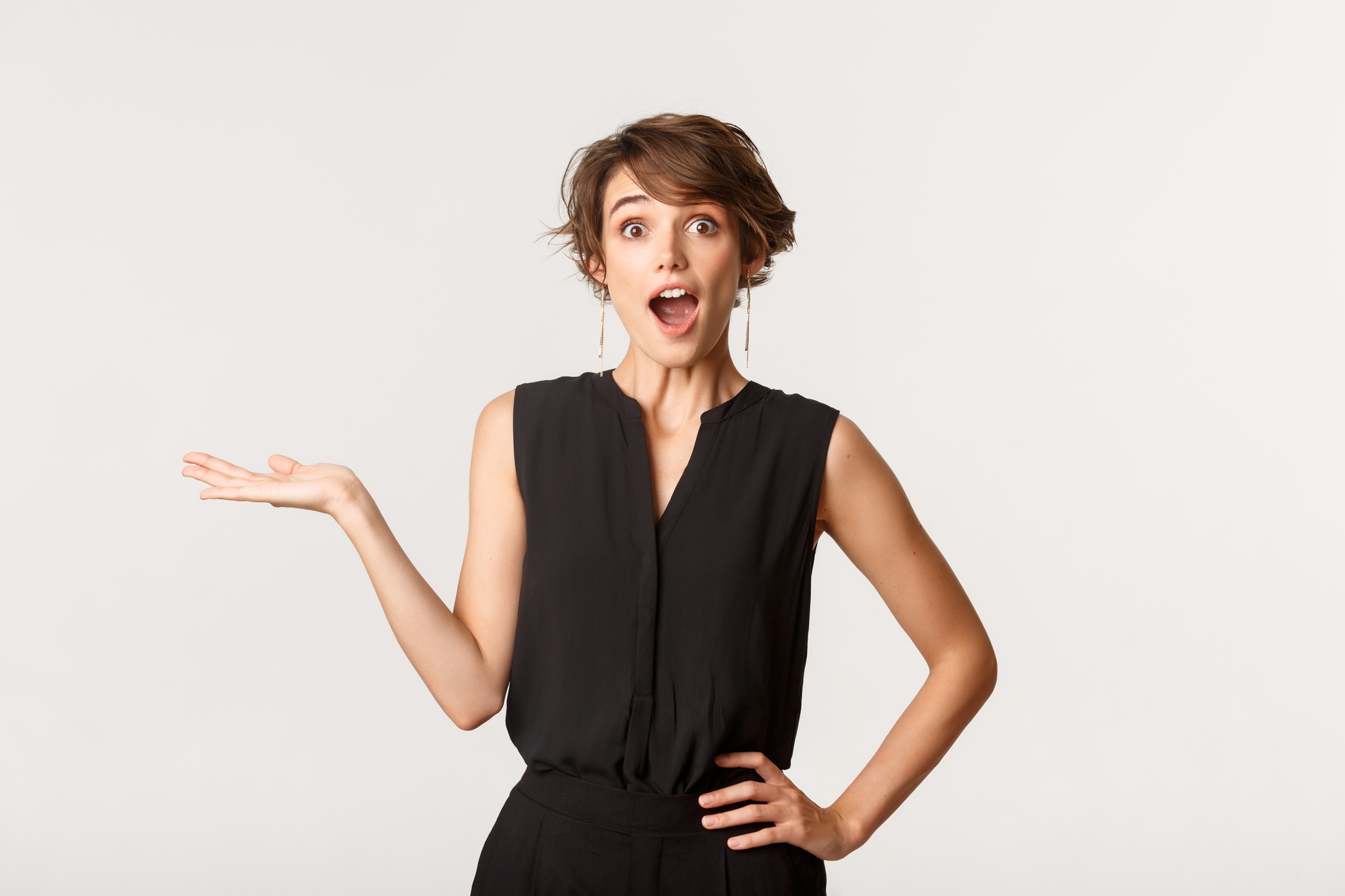 Surprised and amazed young businesswoman holding your logo or product on her palm, open mouth