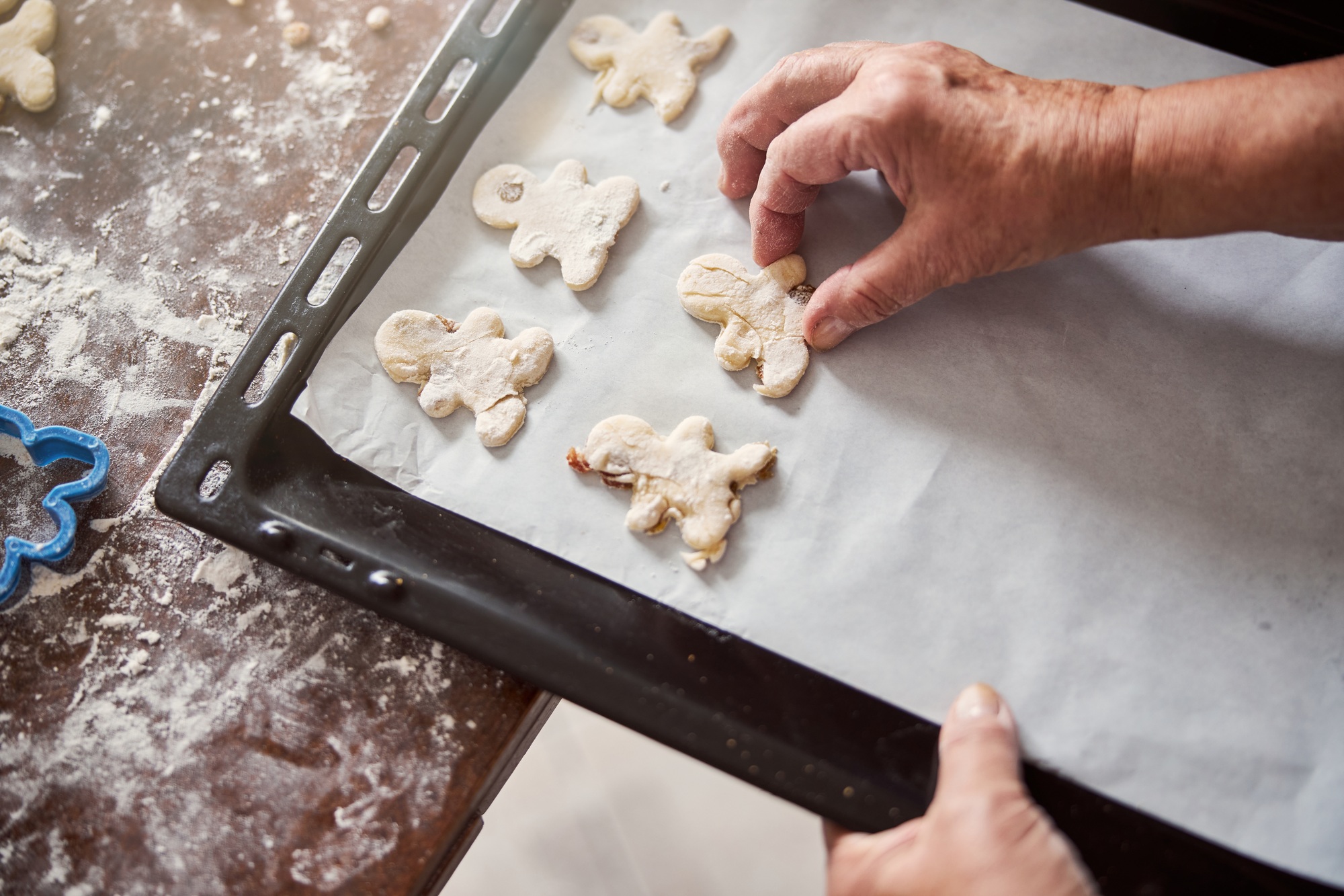 Talented baker putting shaped dough onto baking sheet