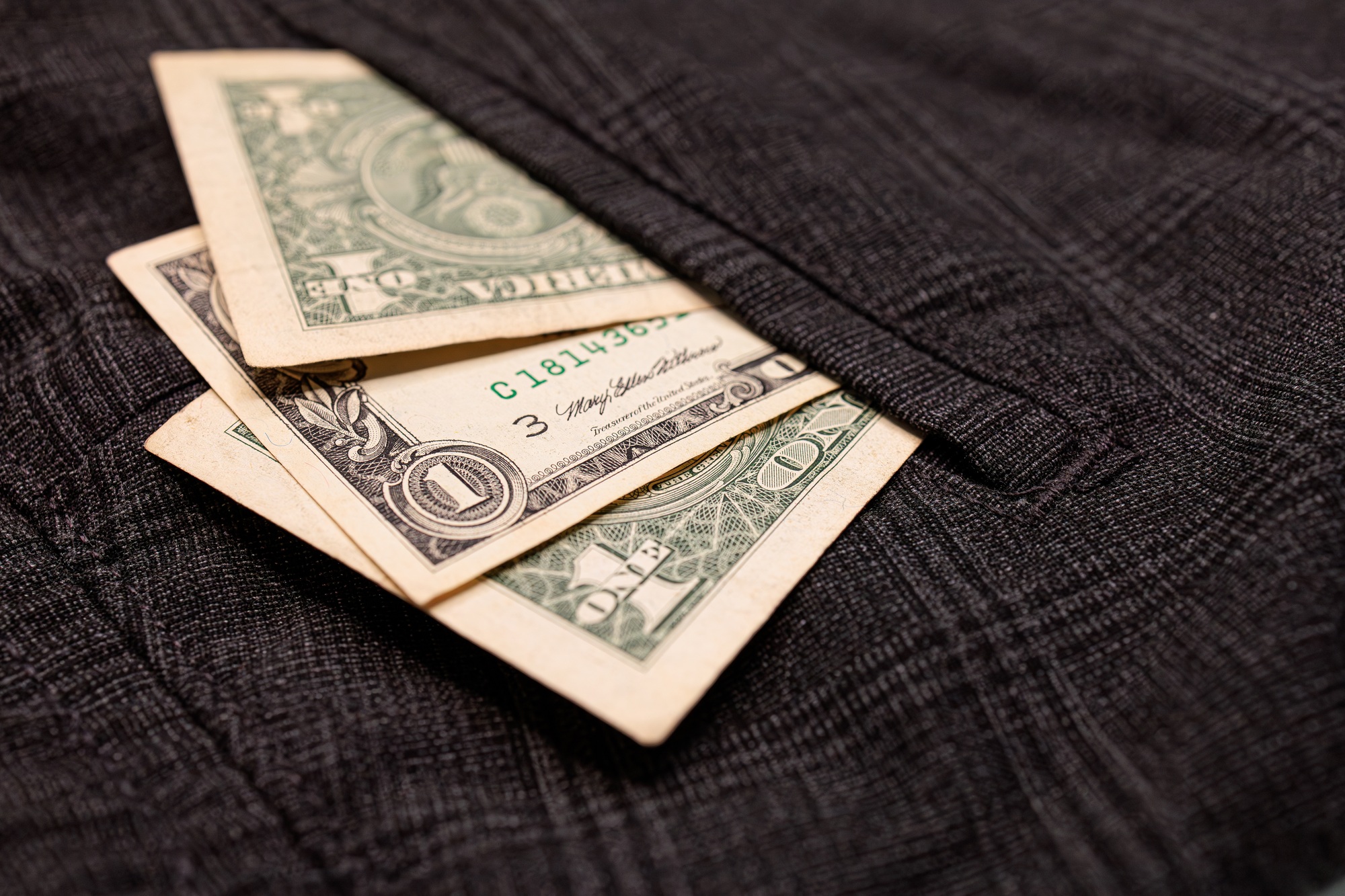 There are dollar bills sticking out of his pocket.