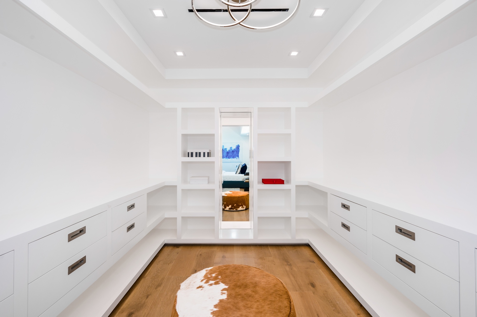 this room has a large white book case in it, along with a cow rug