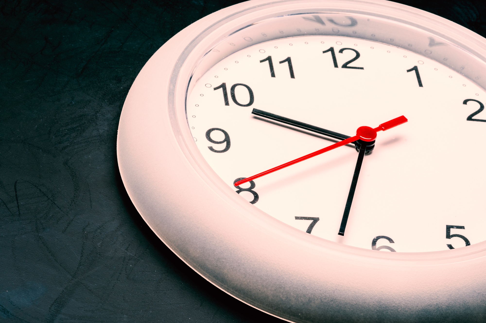 Time management, close up of an analog clock on dark background