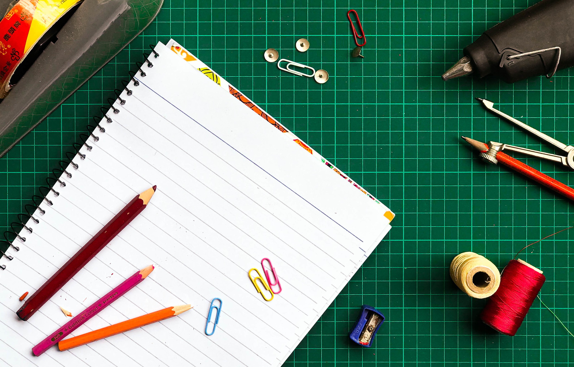 Top view of a green gridded desk with various stationery