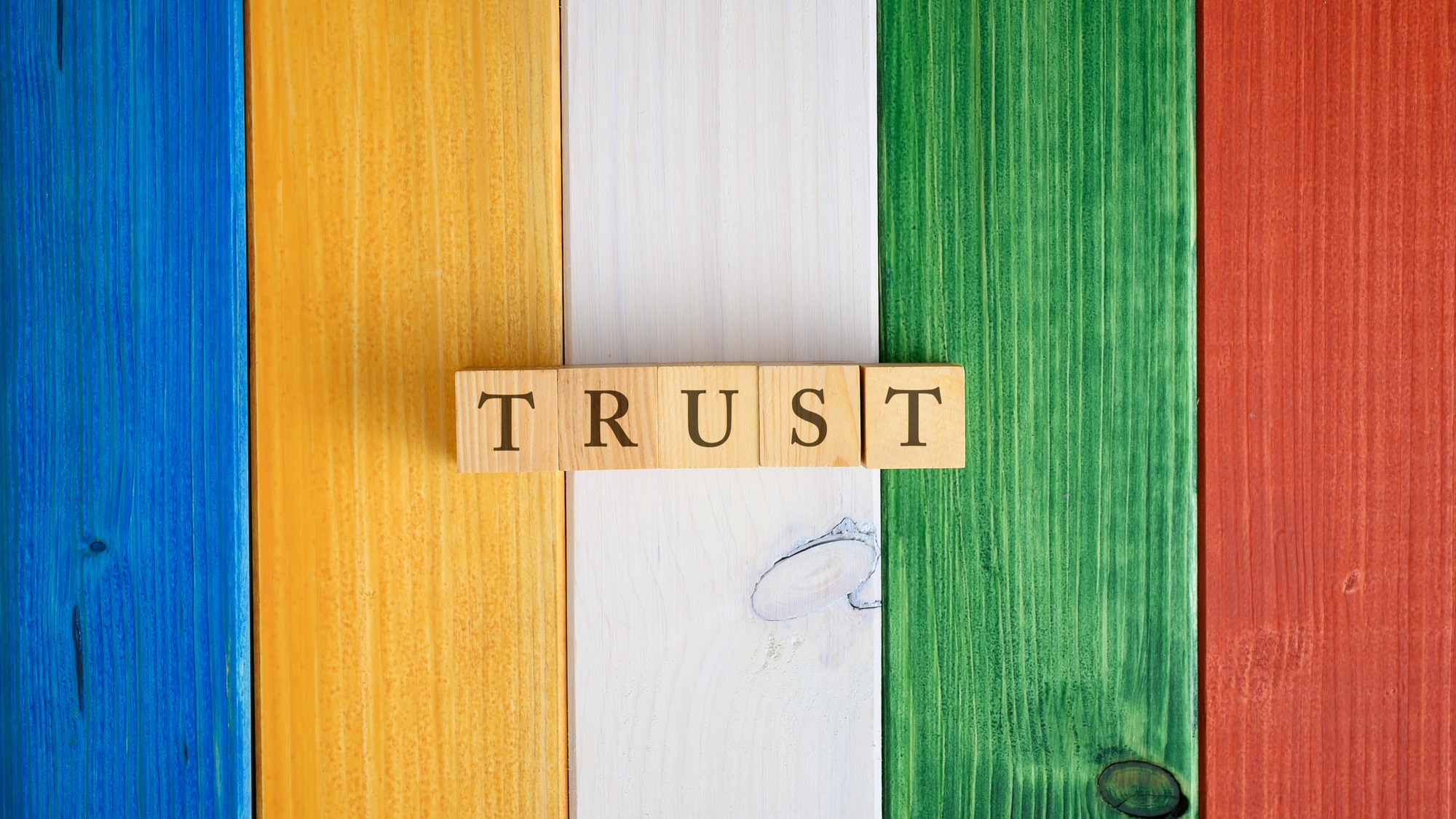 Top view of the word Trust spelled on wooden cubes