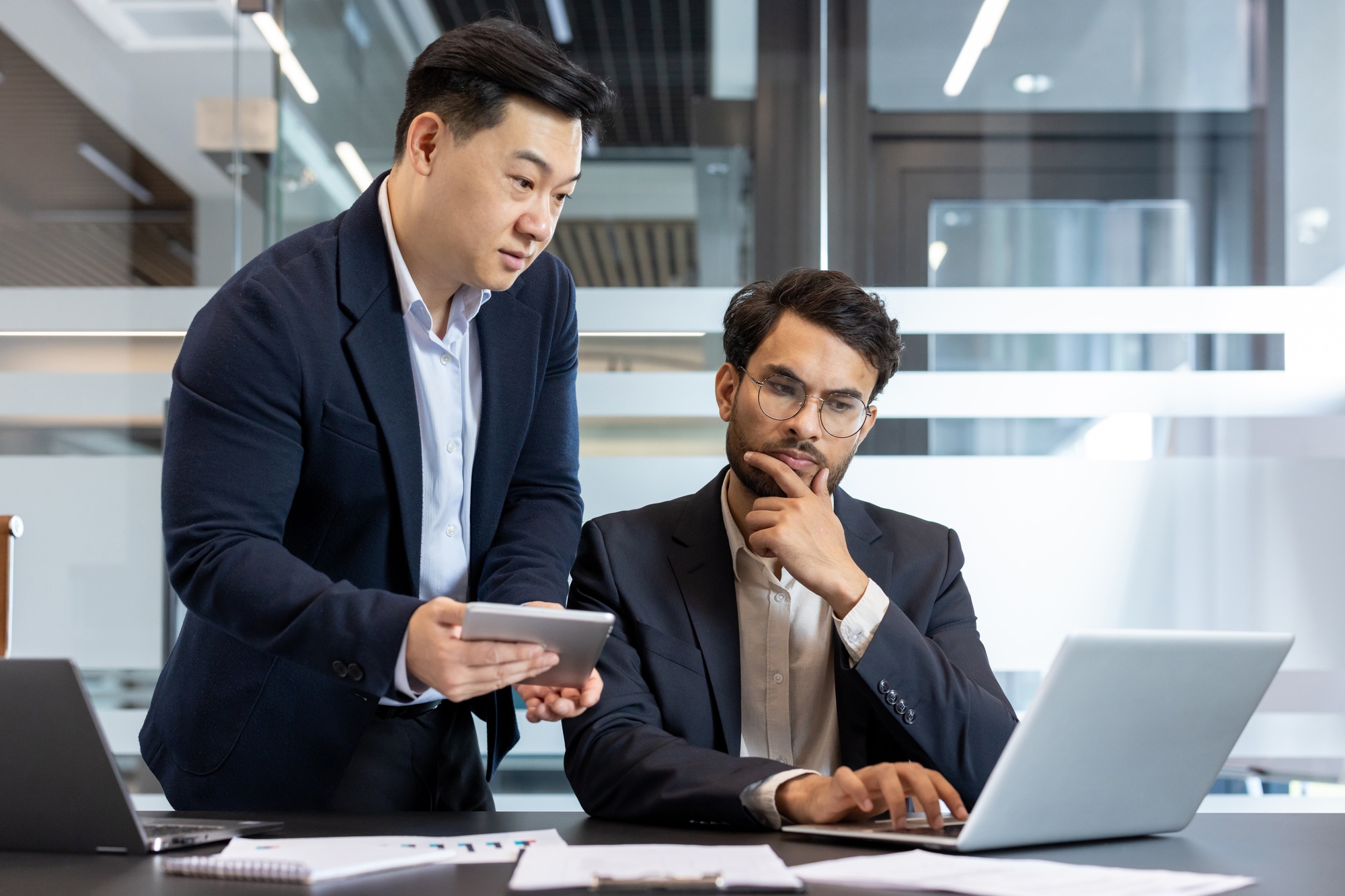 Two business colleagues discussing project strategies on a laptop and phone