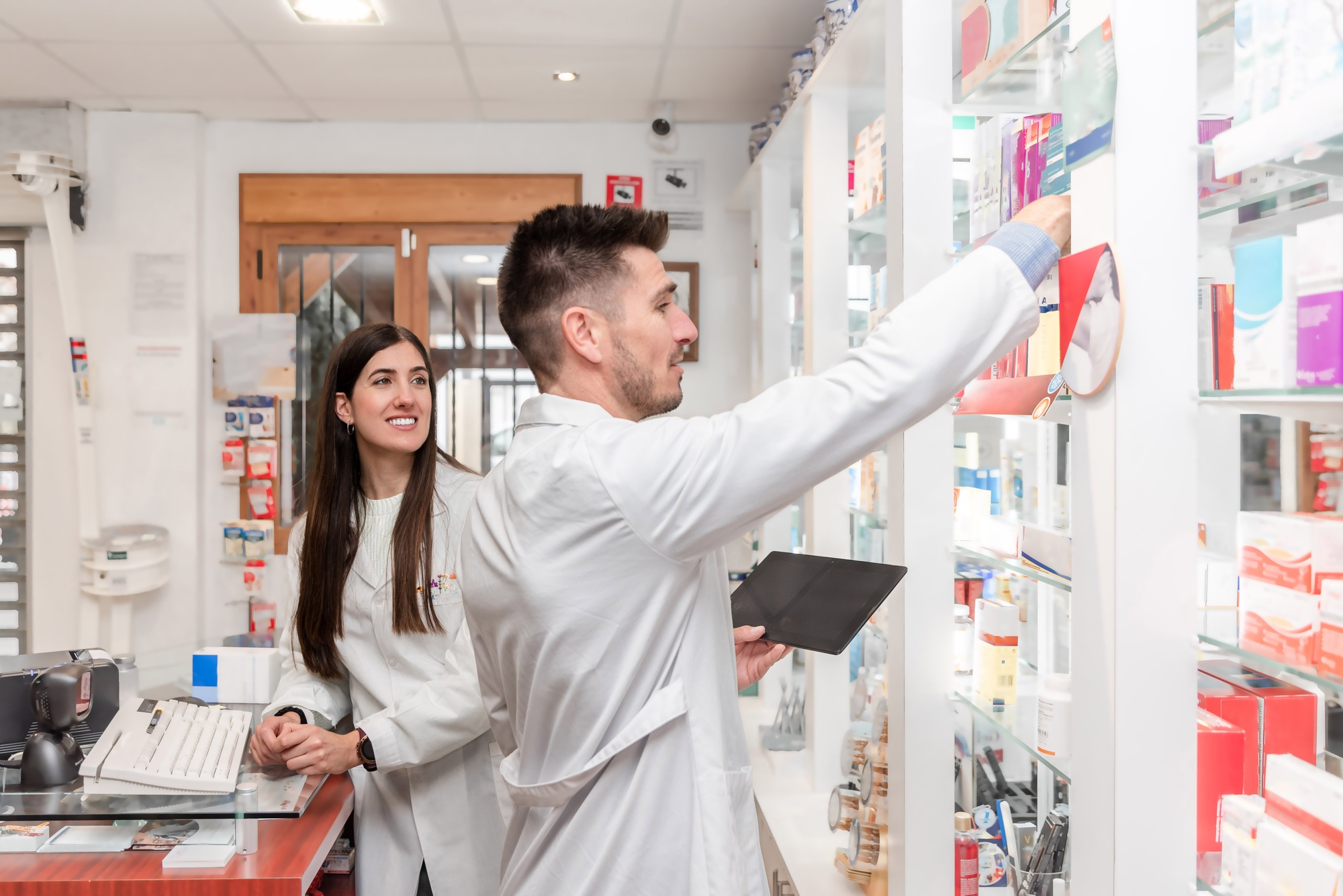 Two diverse Pharmacists managing inventory and checking medicine stock in pharmacy