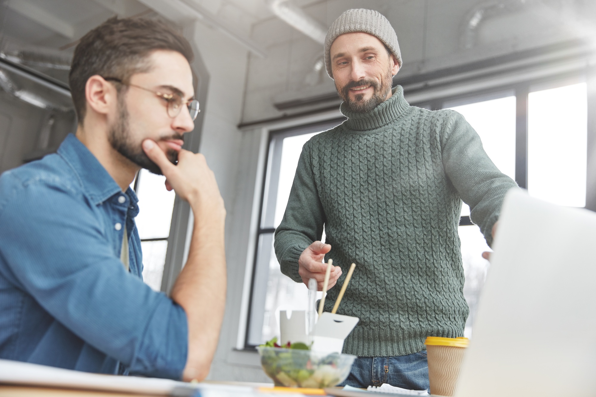 Two male bloggers choose multimedia files for publishing on their website, have informal meeting, ea