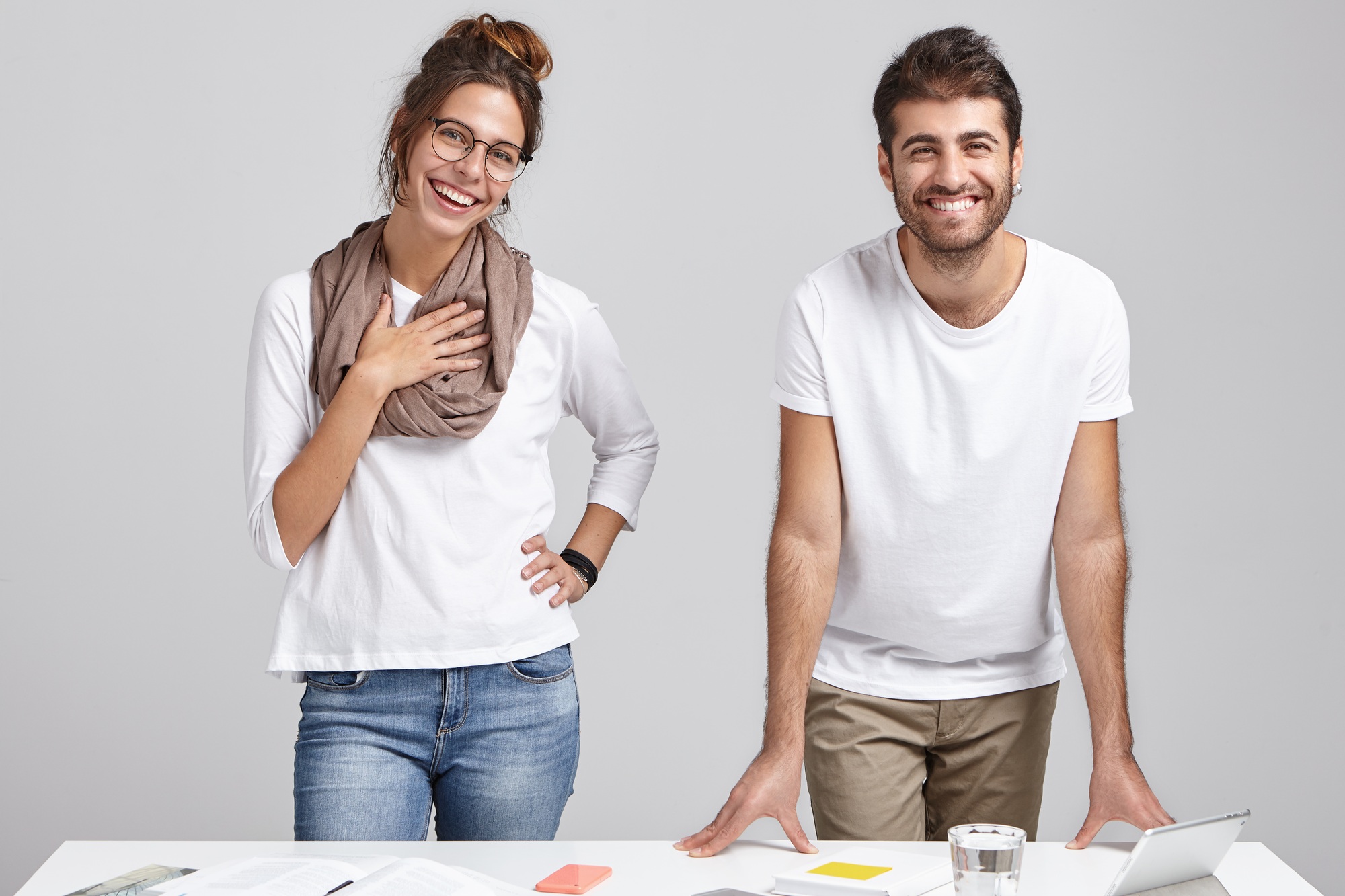 Two young colleagues have meeting, work with business papers and modern gadgets, stand at white offi
