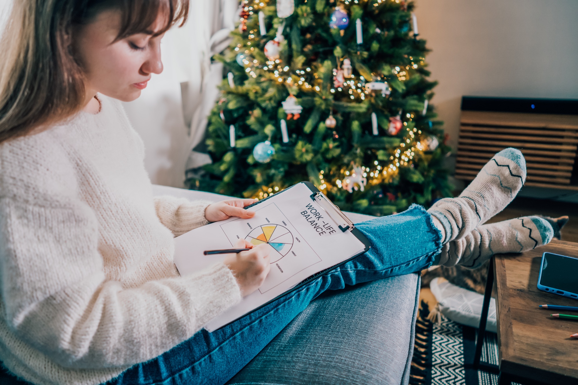 Woman drawing work-life balance wheel sitting on the sofa at home. Self-reflection and life planning