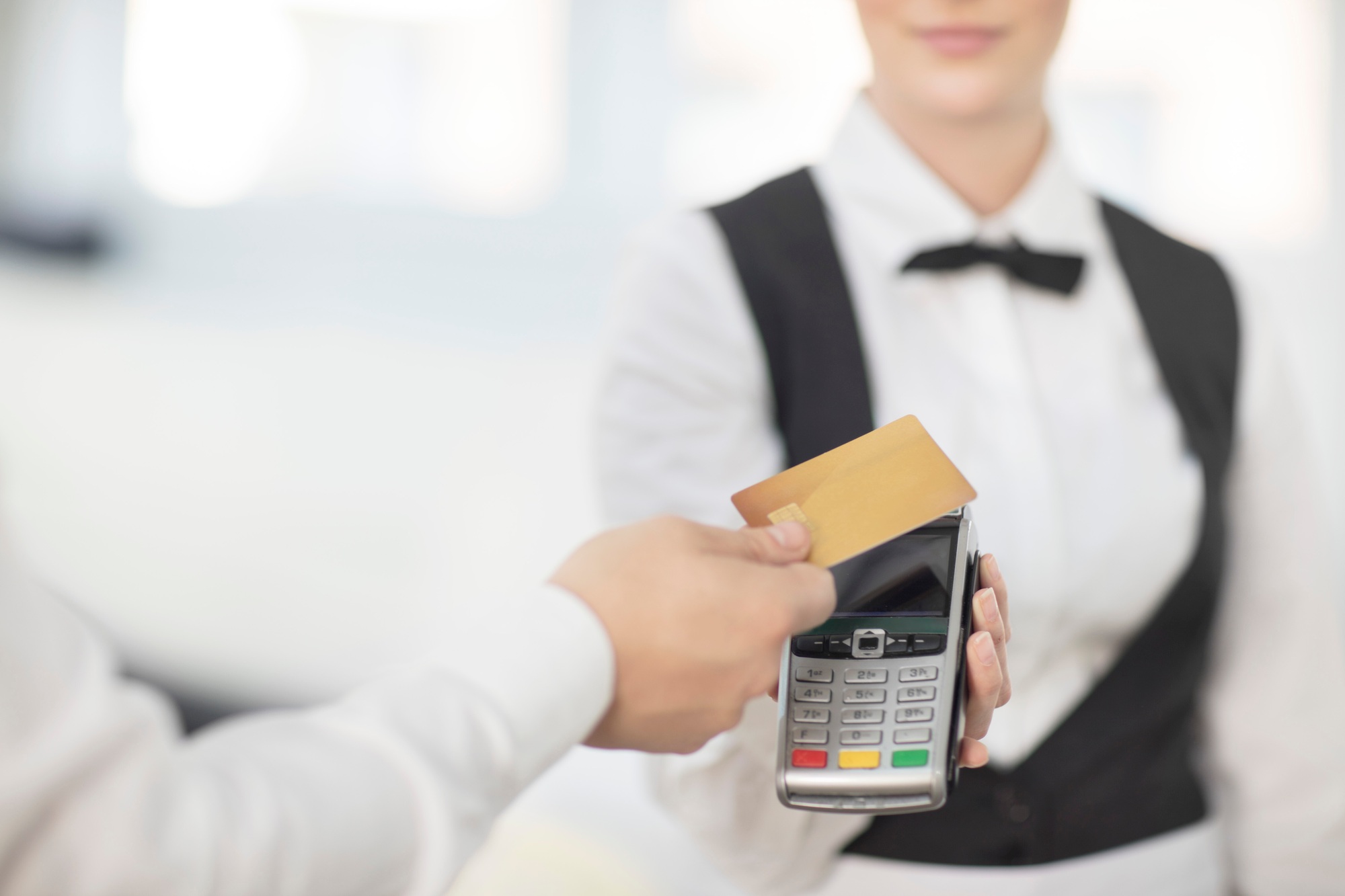 Waitress holding payment machine toward customer, customer paying by contactless method