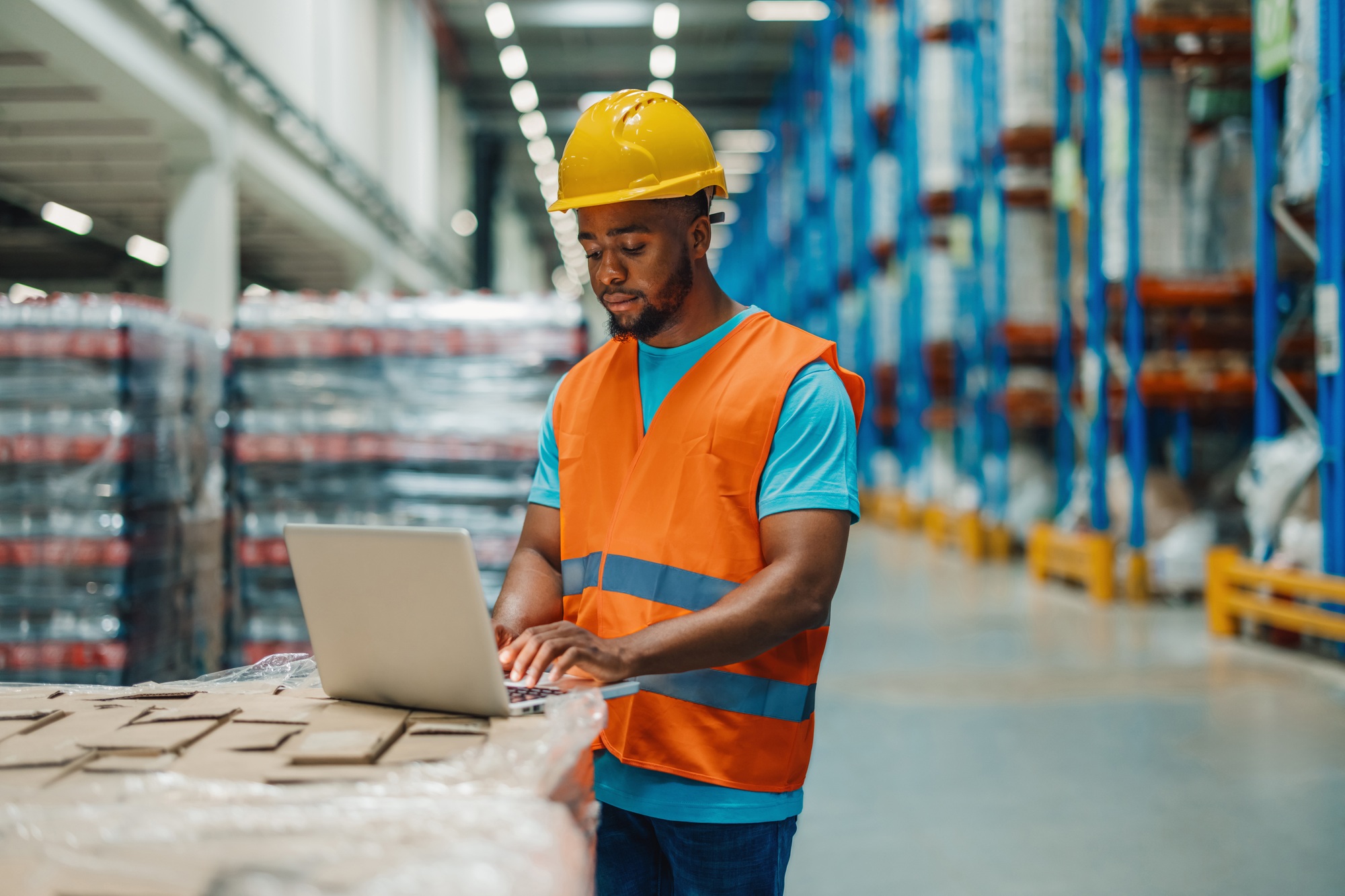 Warehouse worker using laptop managing inventory