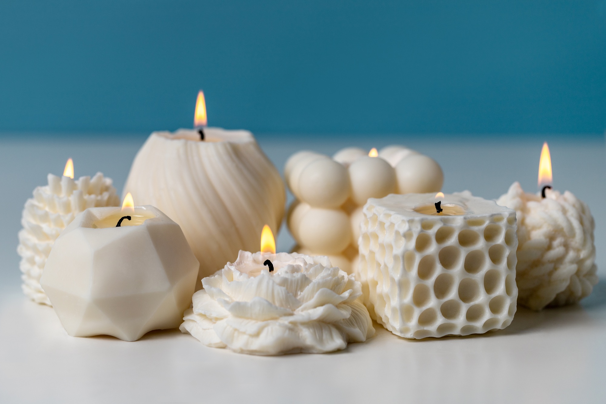 Wax handmade candles on white table against blue background. White naturel scented candle