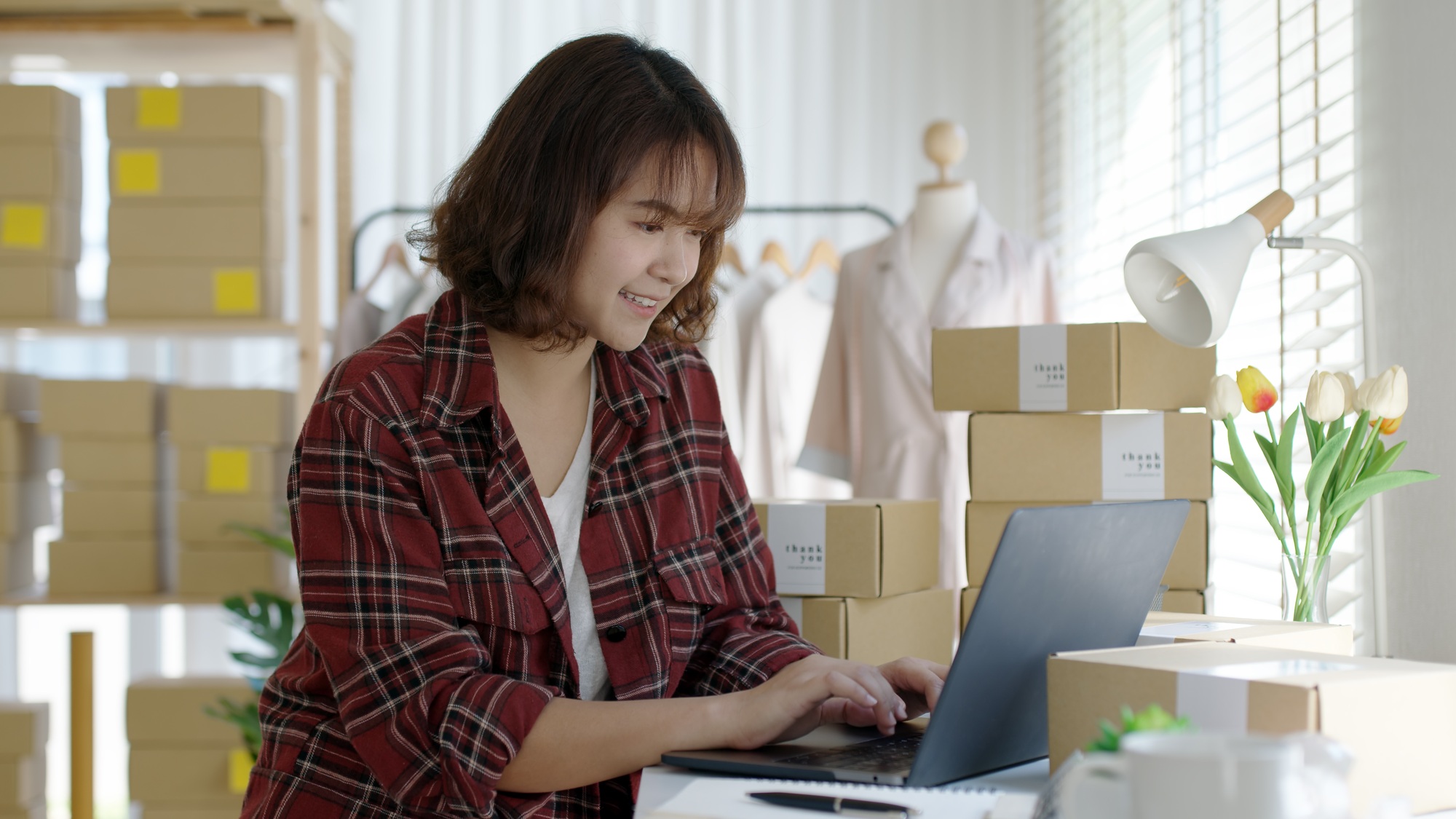 Woman e-commerce parcel typing and talk to customer on notebook for box shipping online