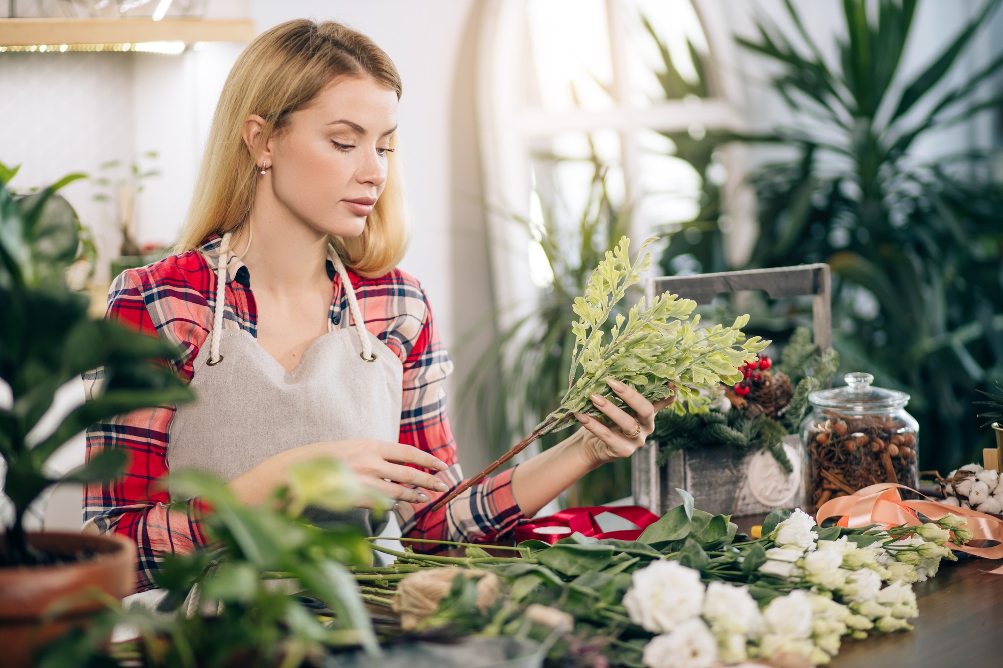woman florist, small business owner checking her fresh flowers, plants stocks and inventory