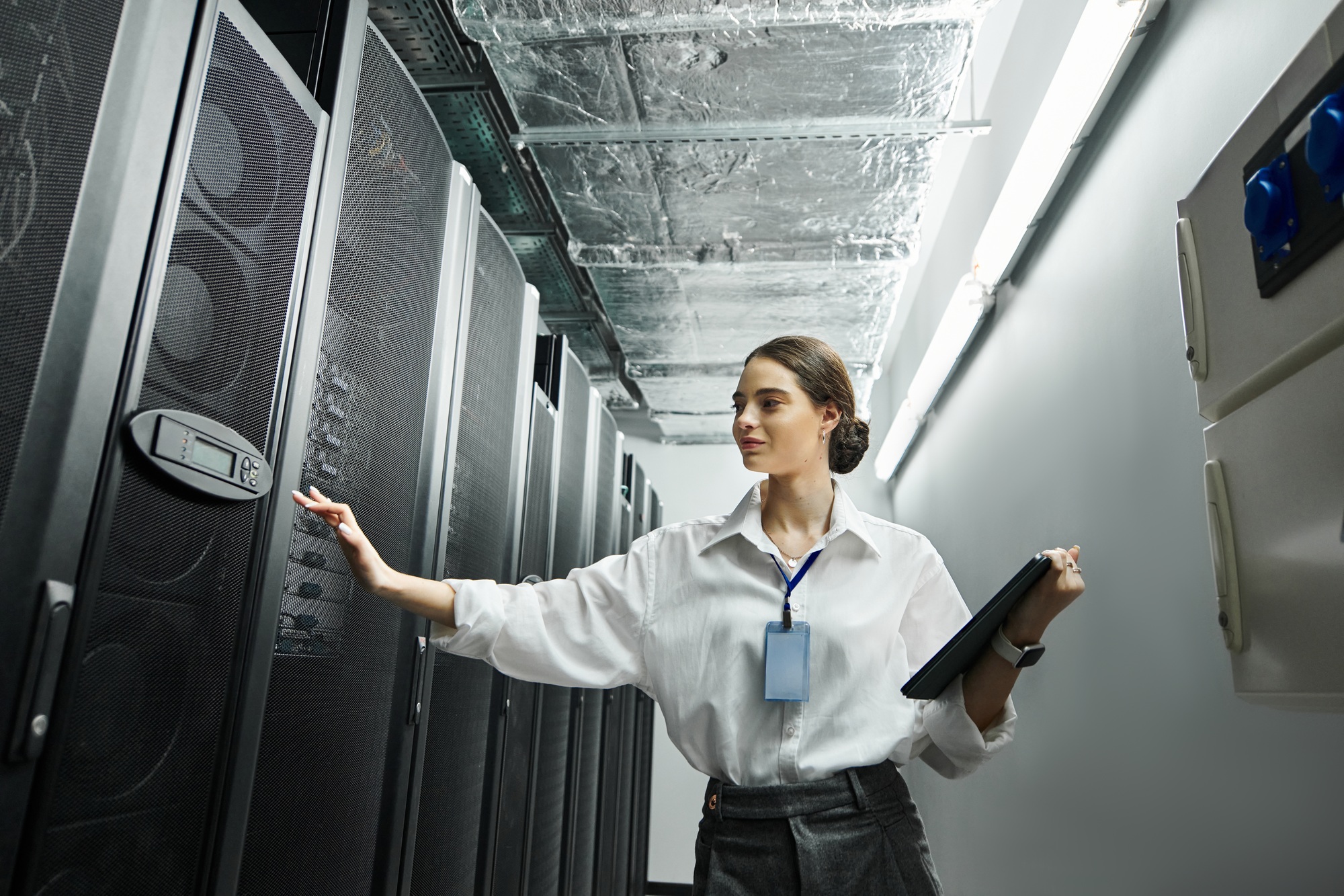 Woman in a white shirt engages with server hardware while maintaining digital security protocols.