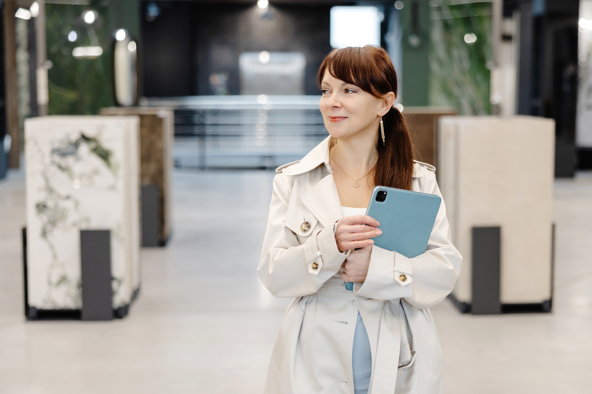 Woman in white coat holding tablet in interior design showroom