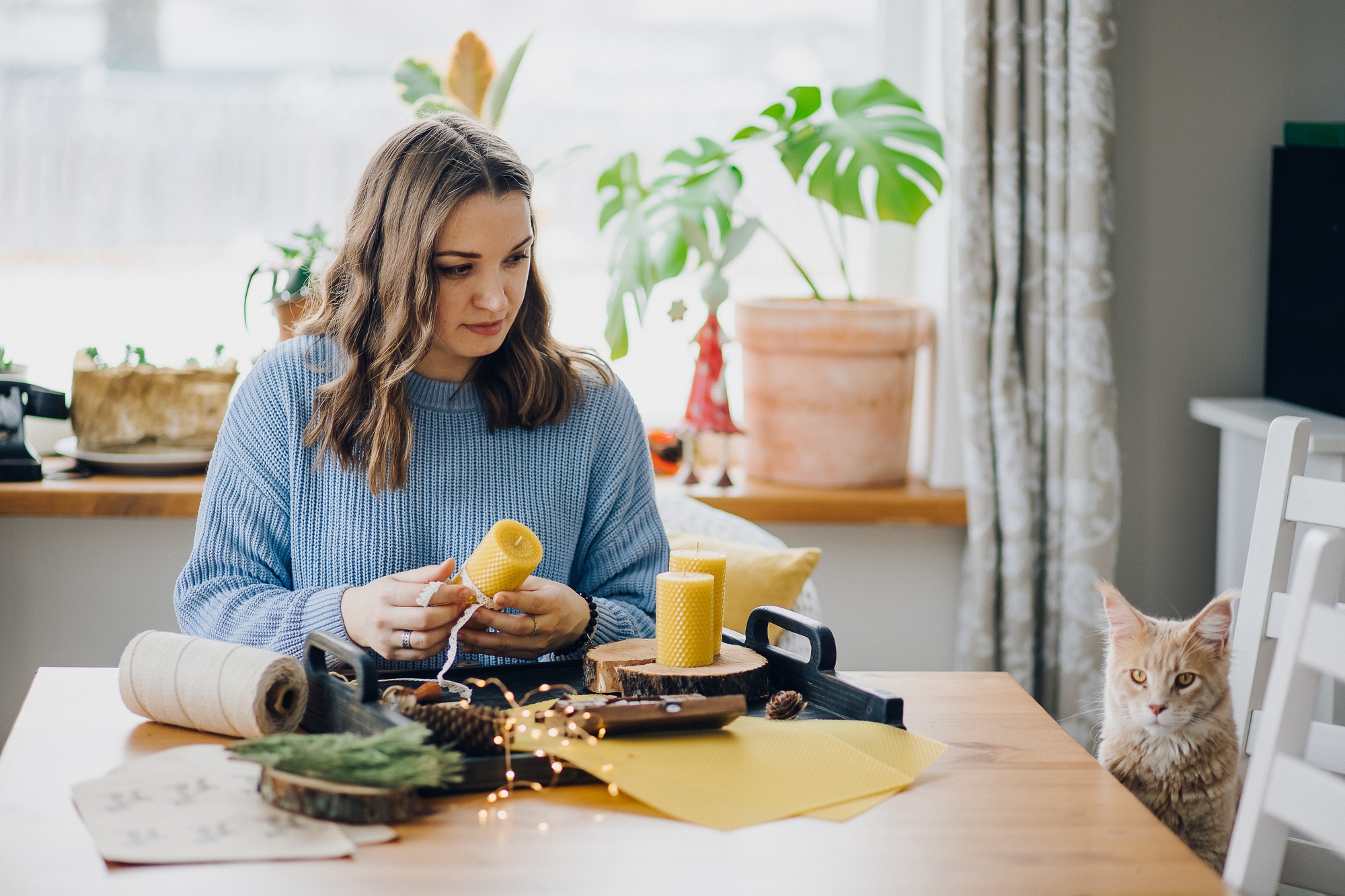 Woman making handmade craft natural wax candles and a cat