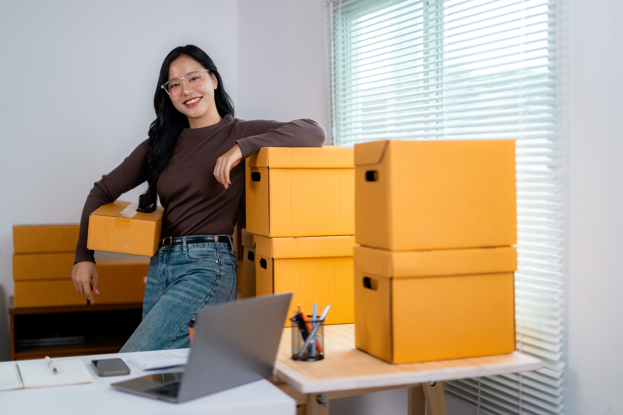 Woman managing inventory with stacked boxes in office