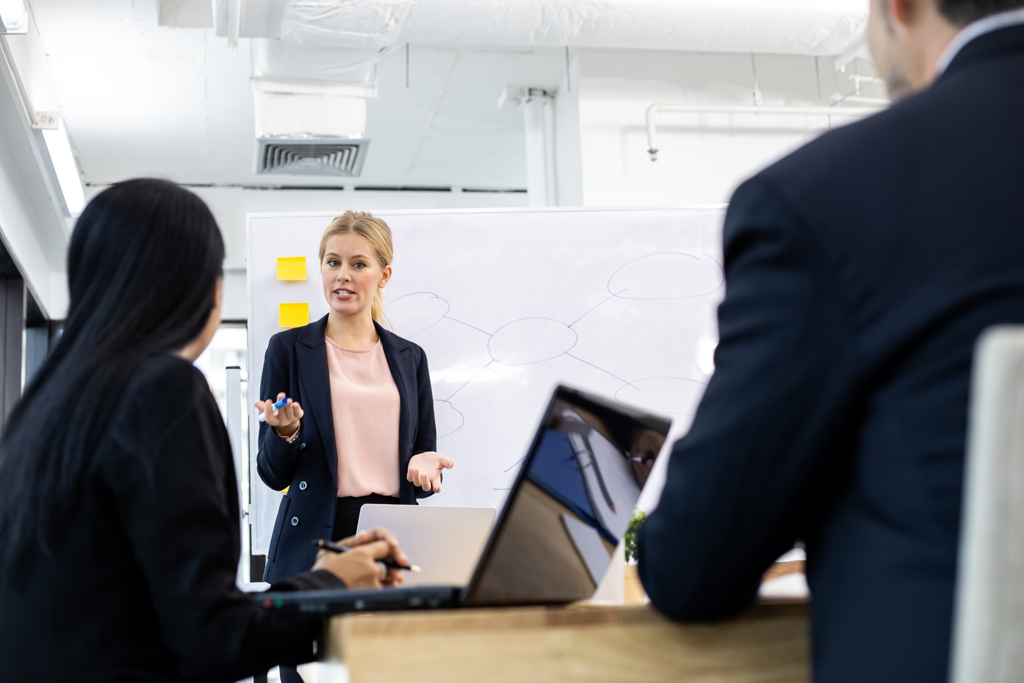 Woman offering information on board to team.