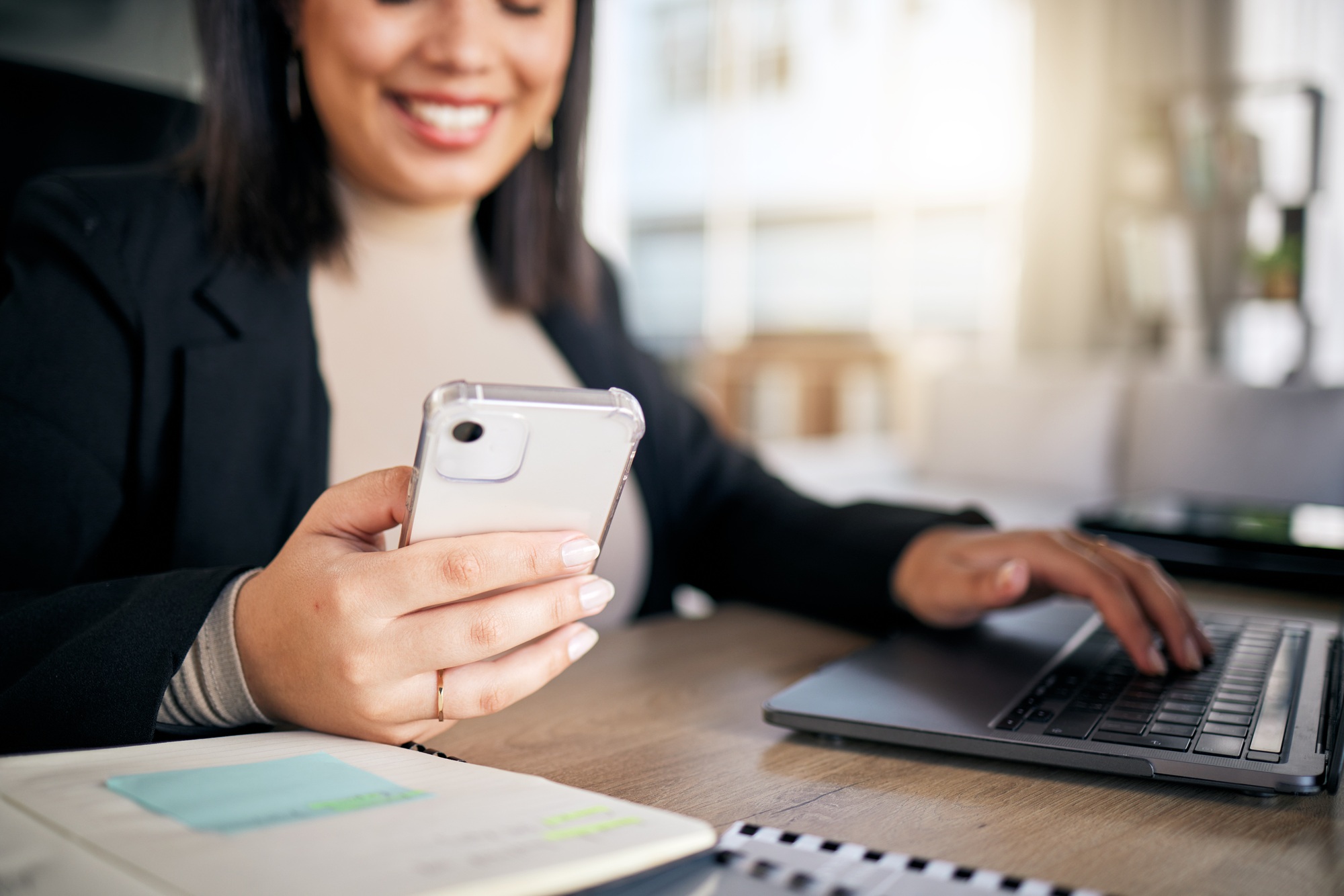 Woman, typing and laptop in office with phone, thinking and planning post schedule for blog on app.