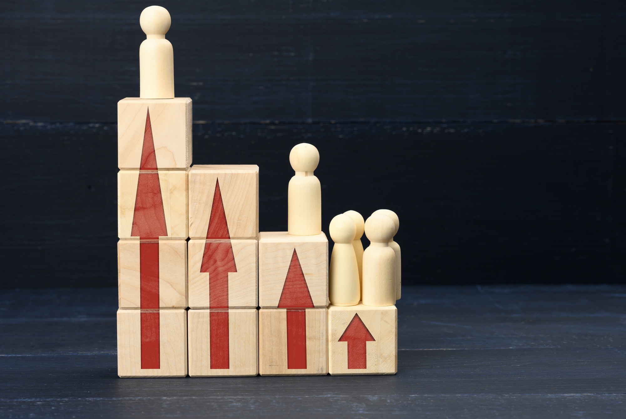 Wooden figures of men on a ladder made of blocks. Concept of career advancement