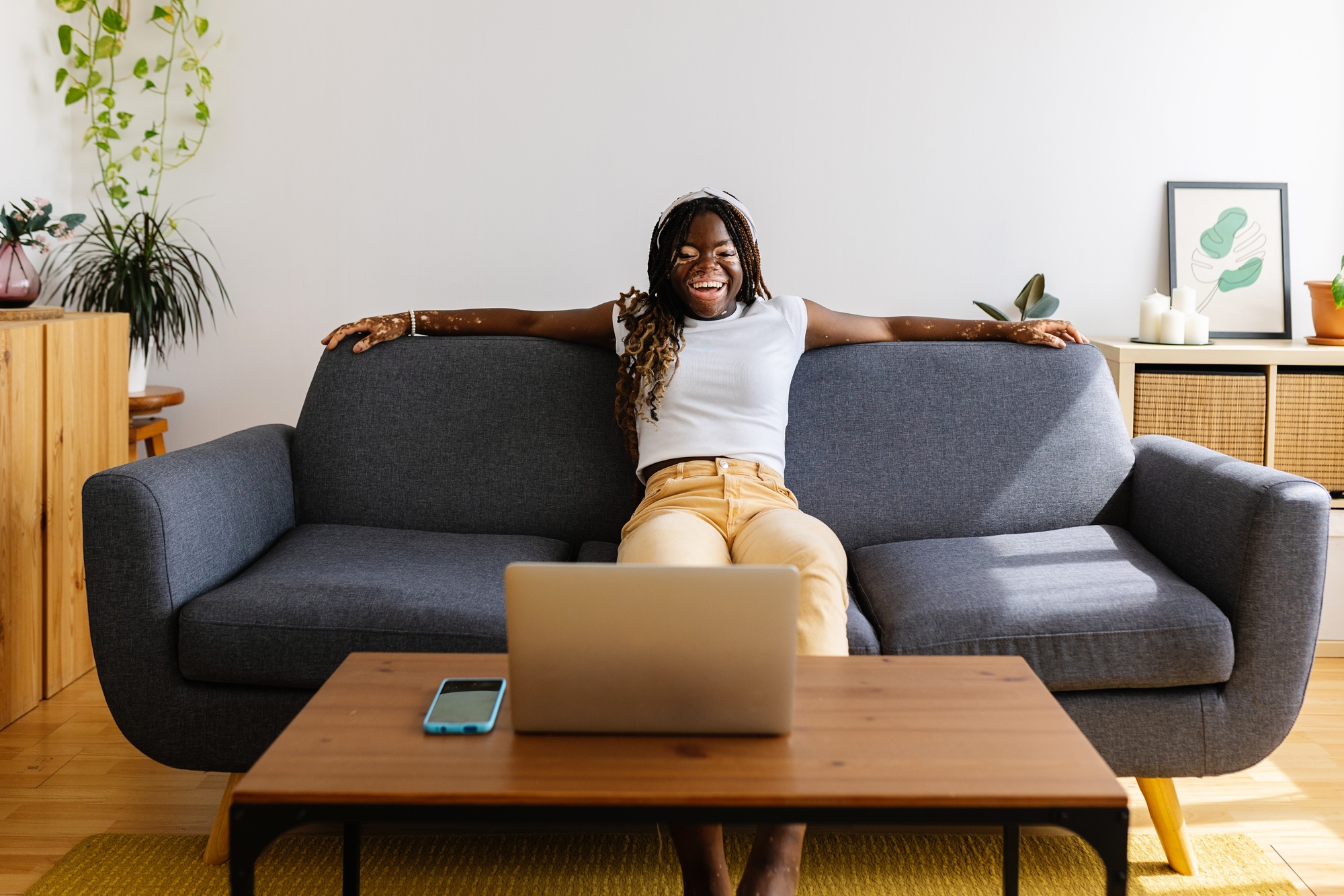 Young african woman having fun watching online videos on laptop at home