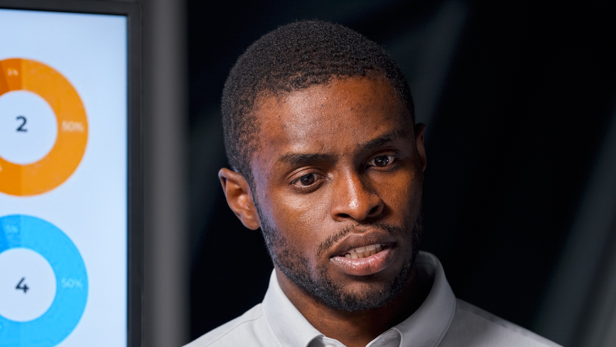 Young afro american businessman listening to questions at presentation
