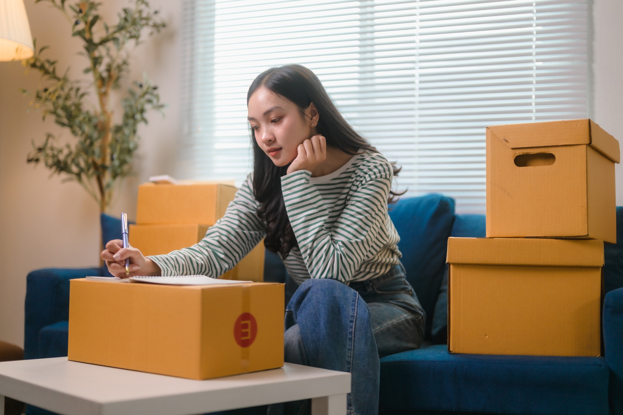 Young Asian Woman Managing Inventory and Writing Delivery Information at Home Office