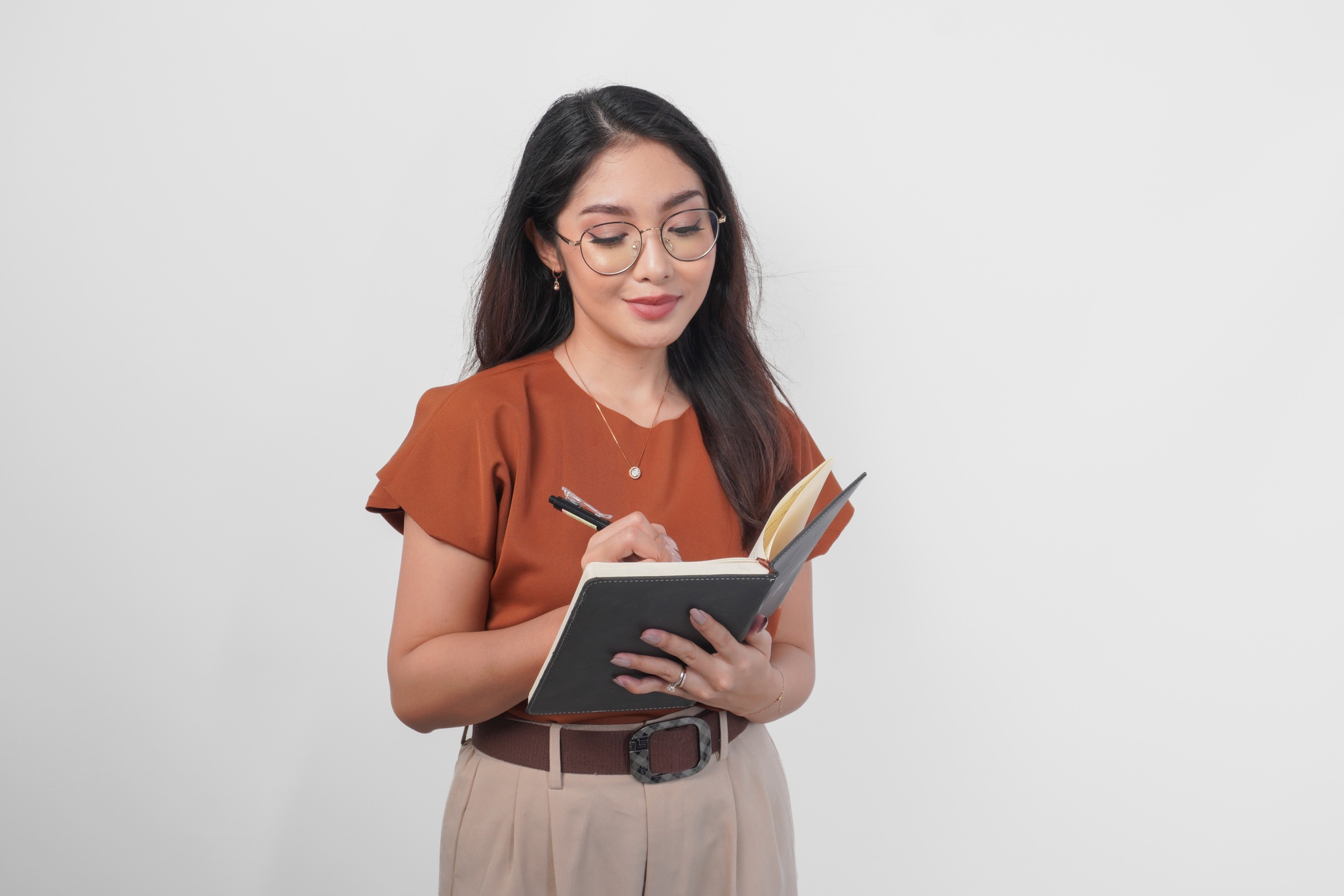 Young Asian women holding book and pen writing task and note in the notebook.