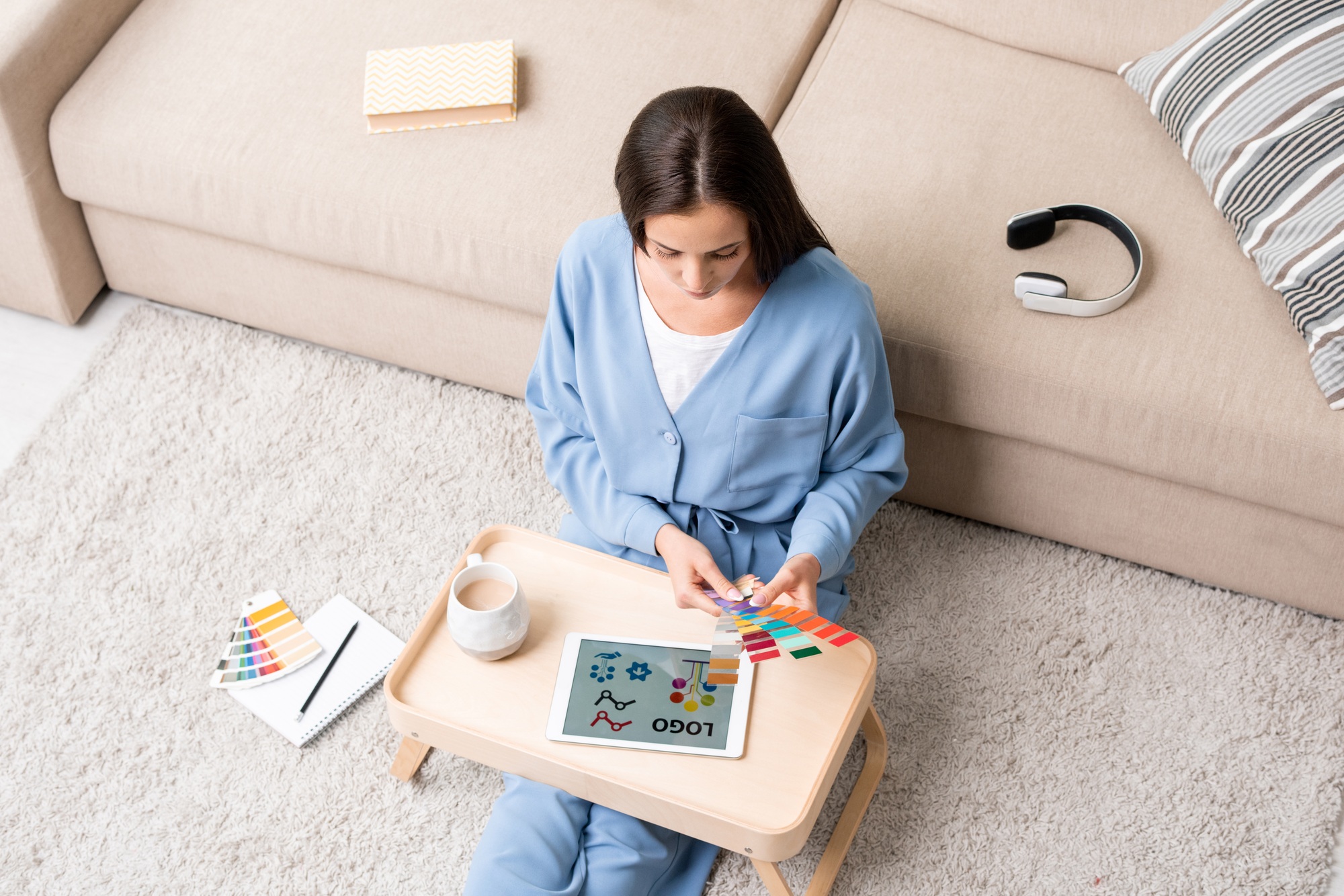 Young brunette female designer in blue pajamas choosing colors for new logo