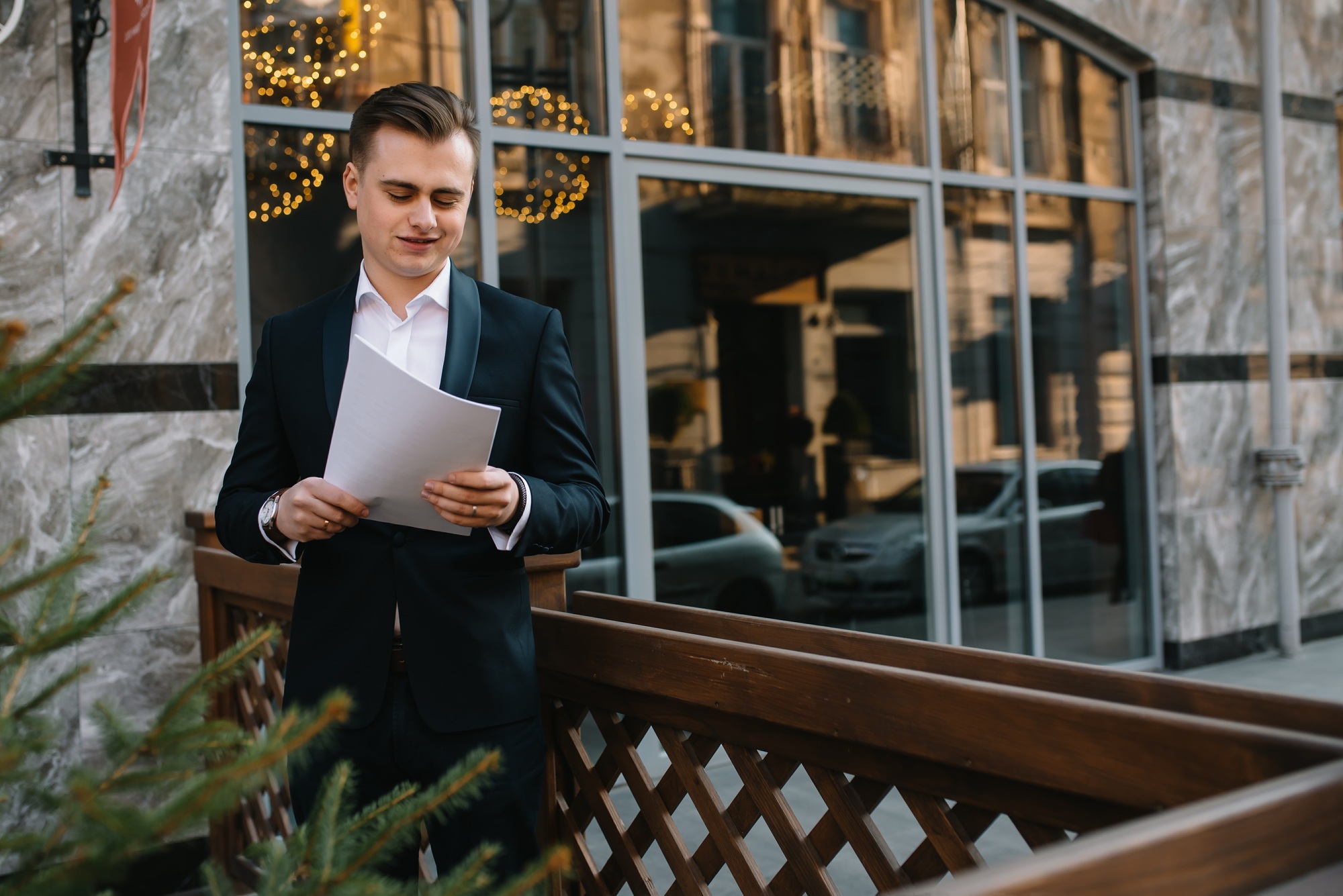 Young business man with documents and mobile phone near of modern building.