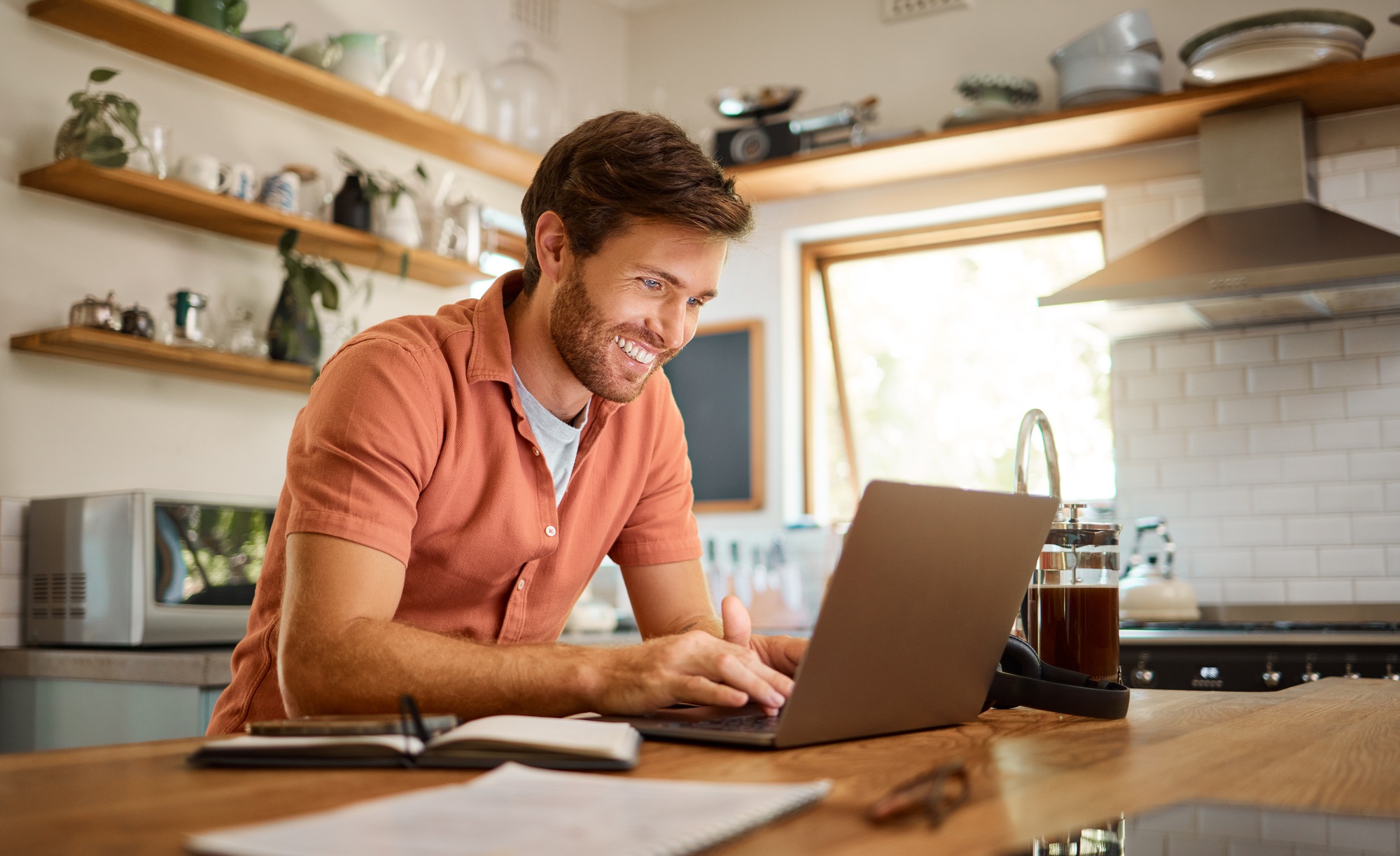 Young cheerful caucasian businessman working on a laptop at home alone. Happy male businessperson s