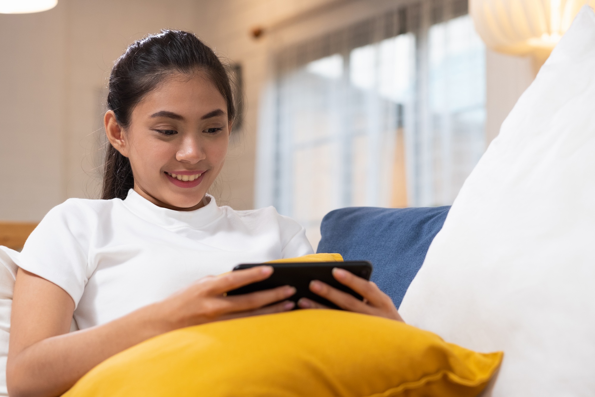 Young happy asian woman watching movie on smartphone
