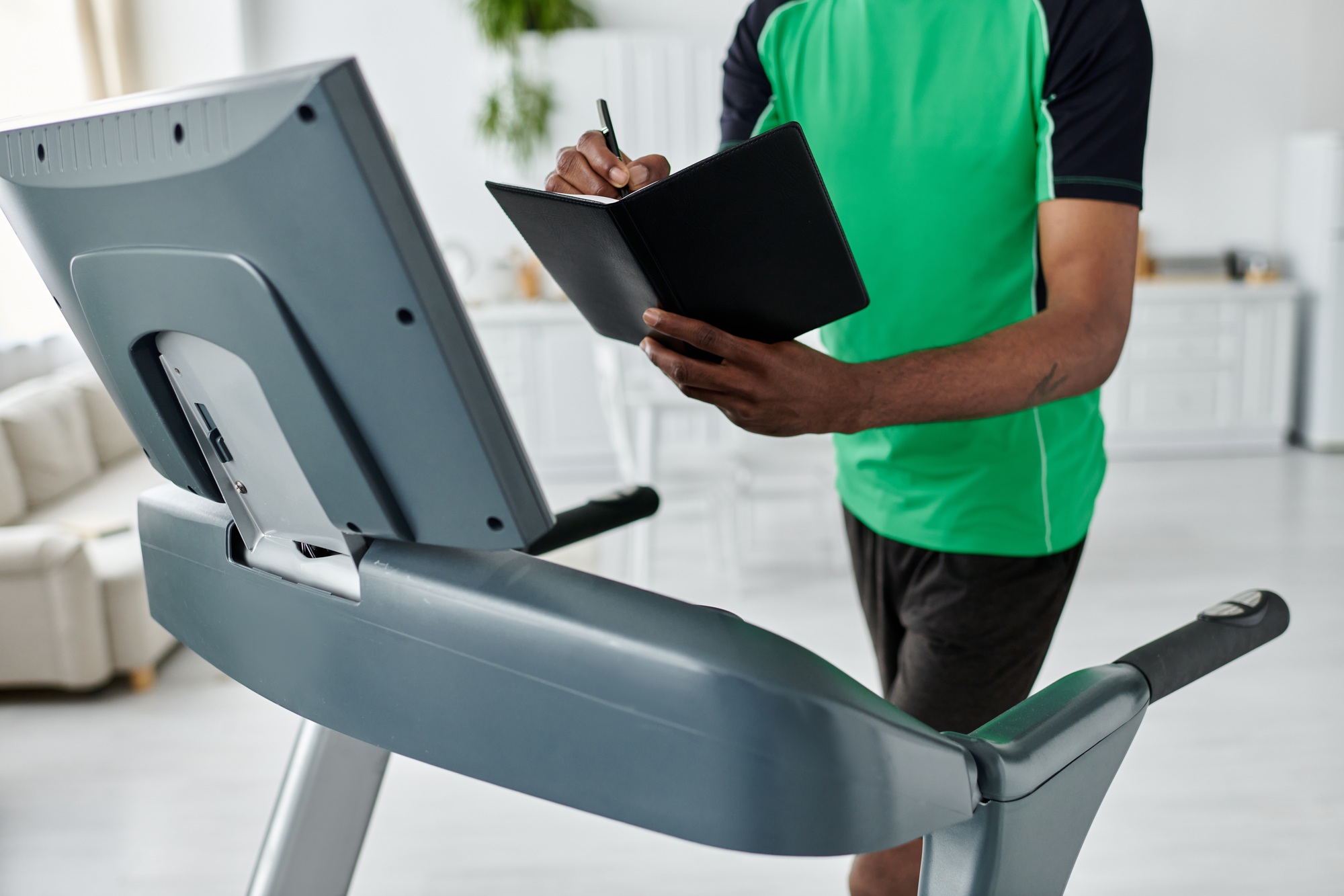 Young man tracks his progress while jogging on a treadmill in a bright modern space