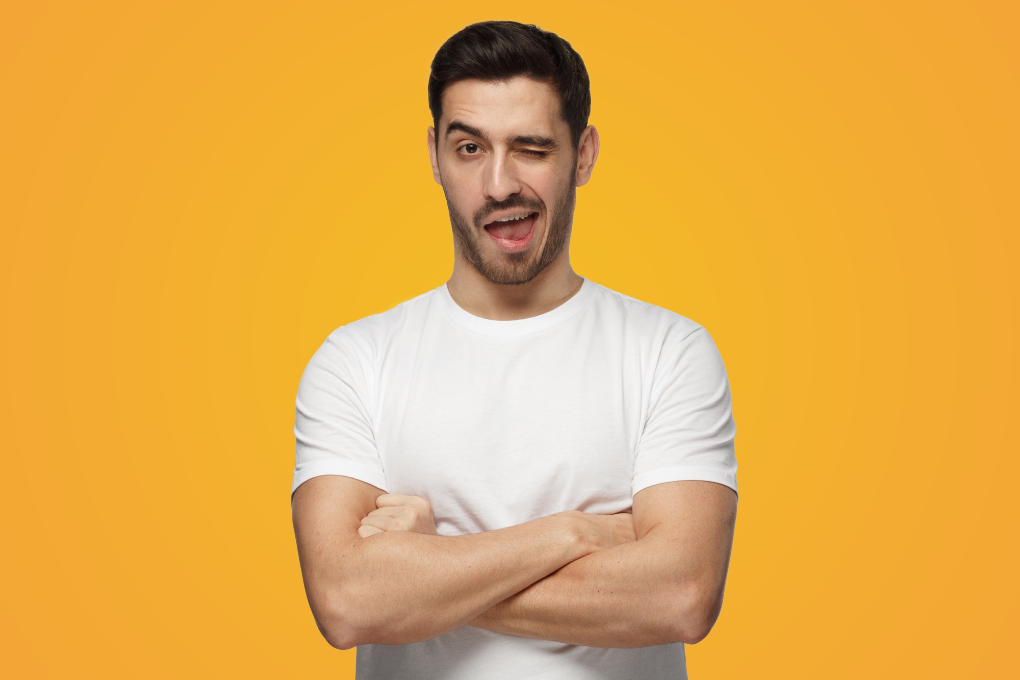 Young man winking friendly as if inviting to adventure or recommending good benefit