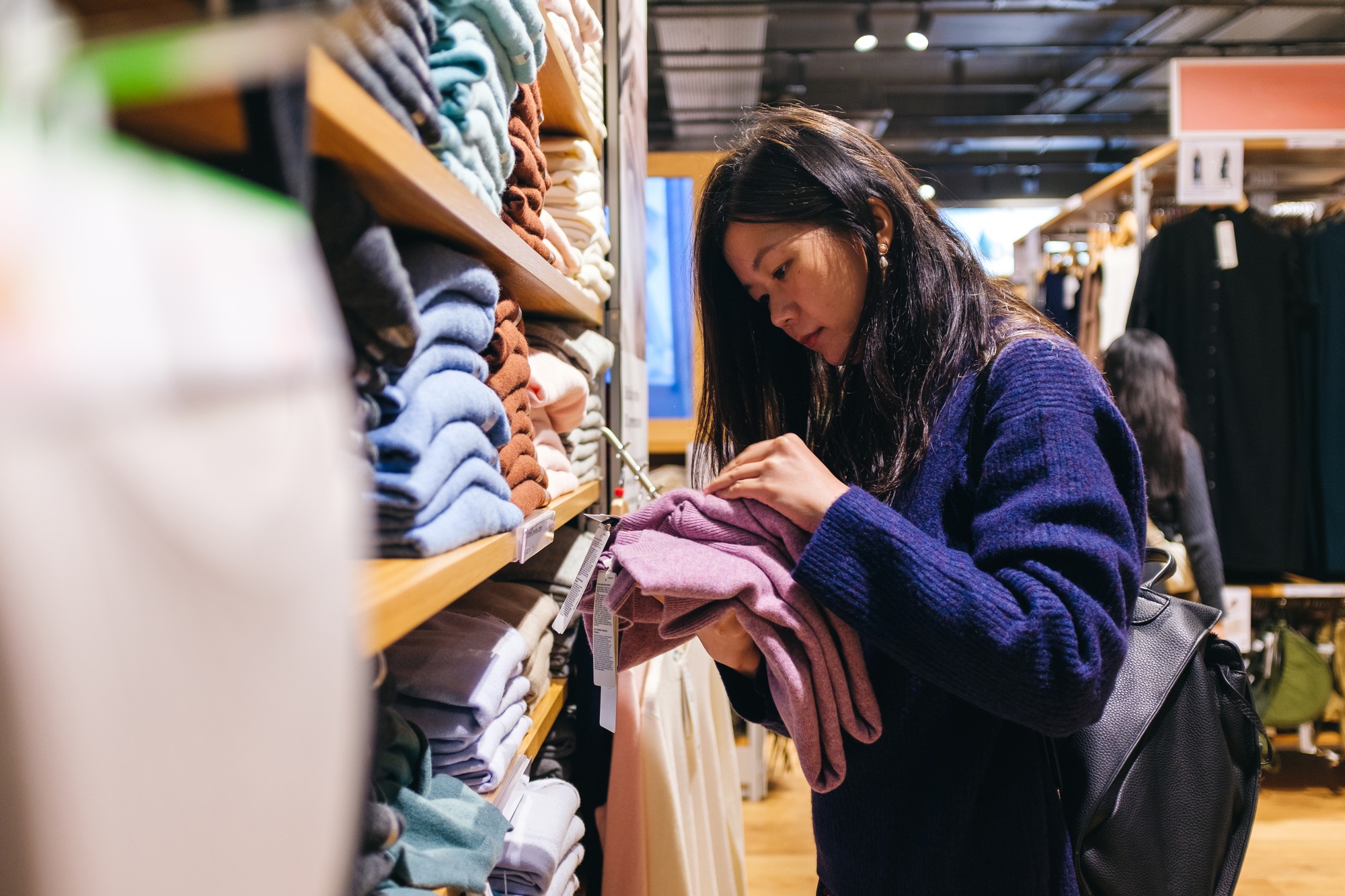 Young woman choosing clothes in clothing store
