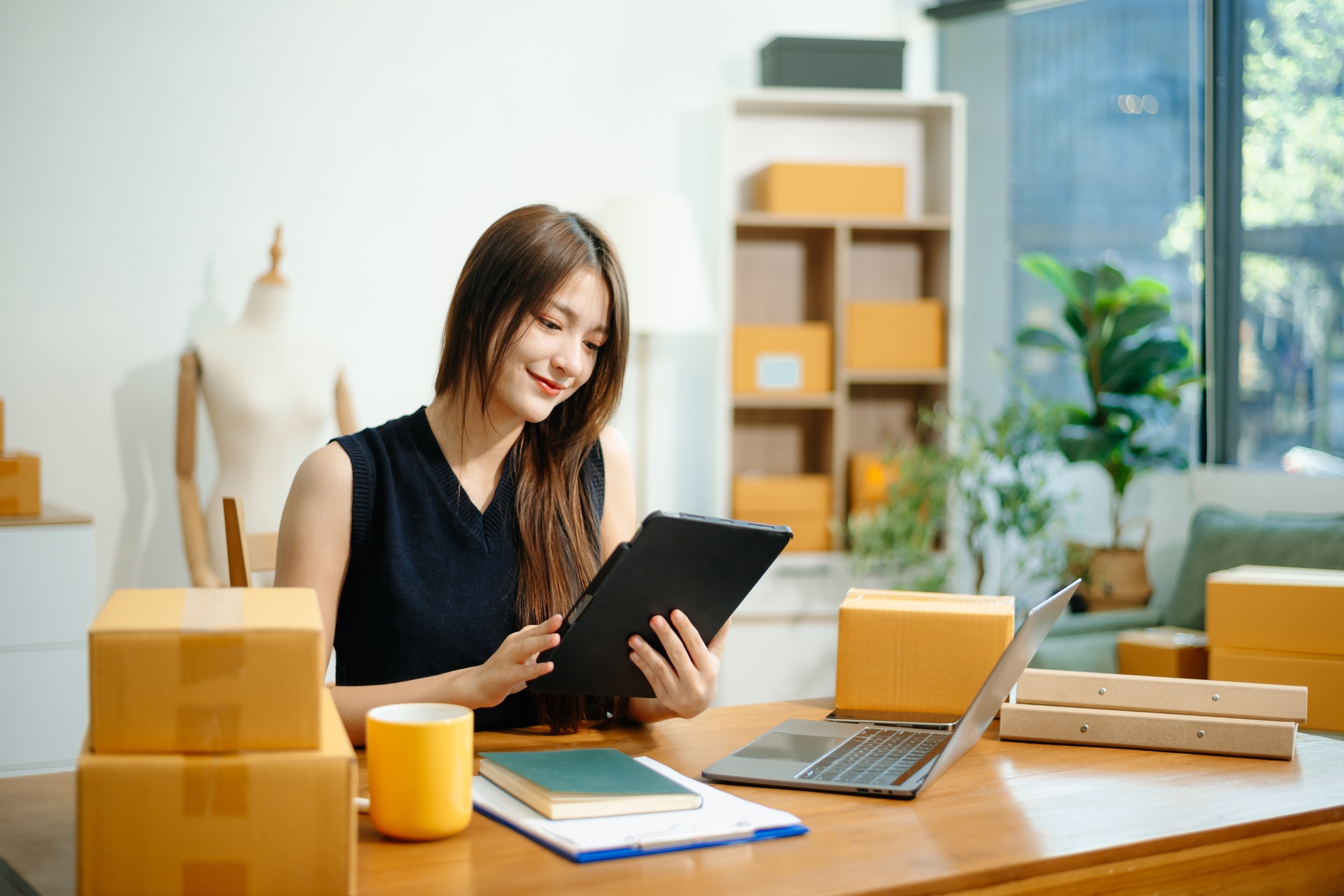 Young woman running online store Startup small business SME, using smartphone or tablet taking