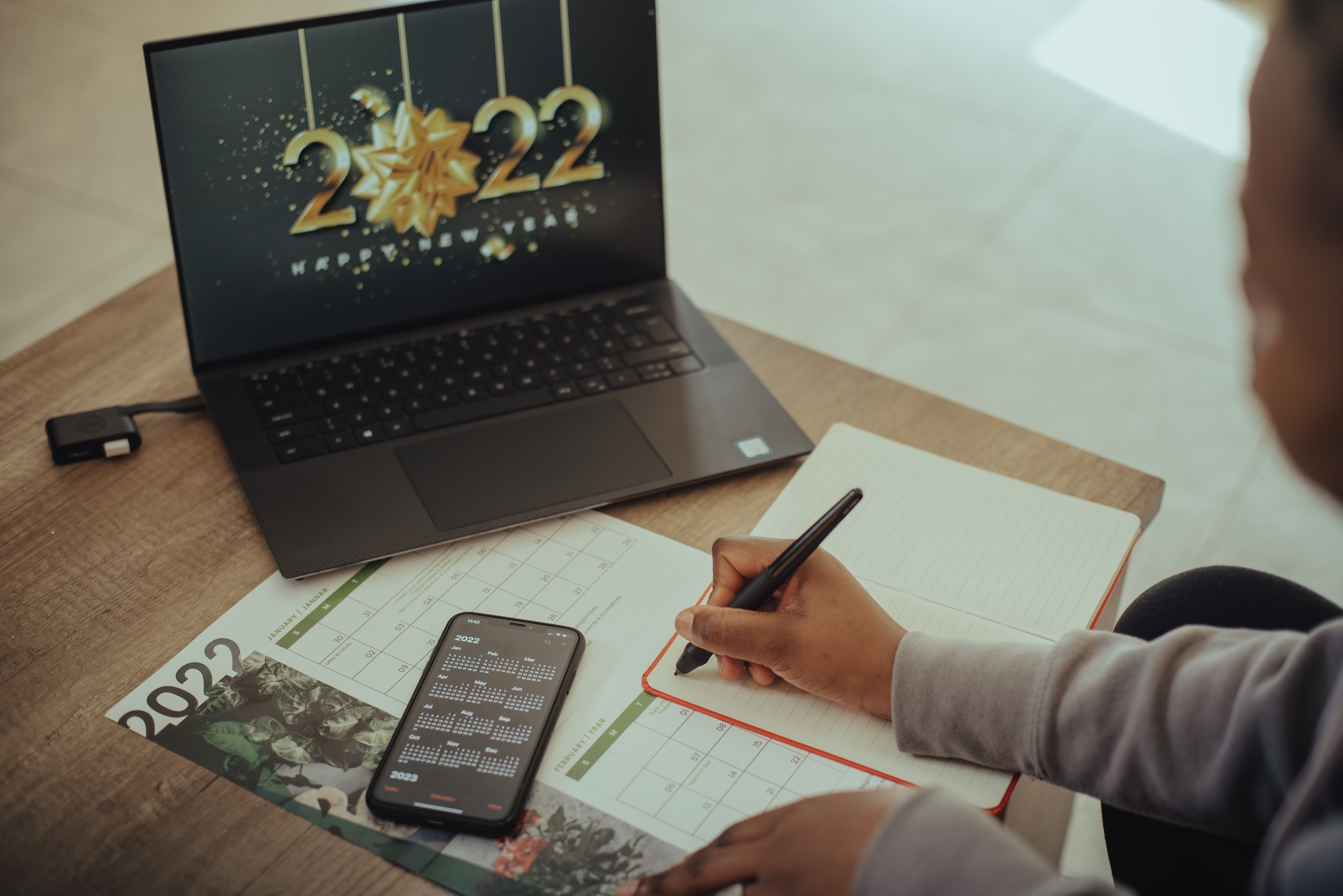 Young woman writing down goals for 2022 in her notebook