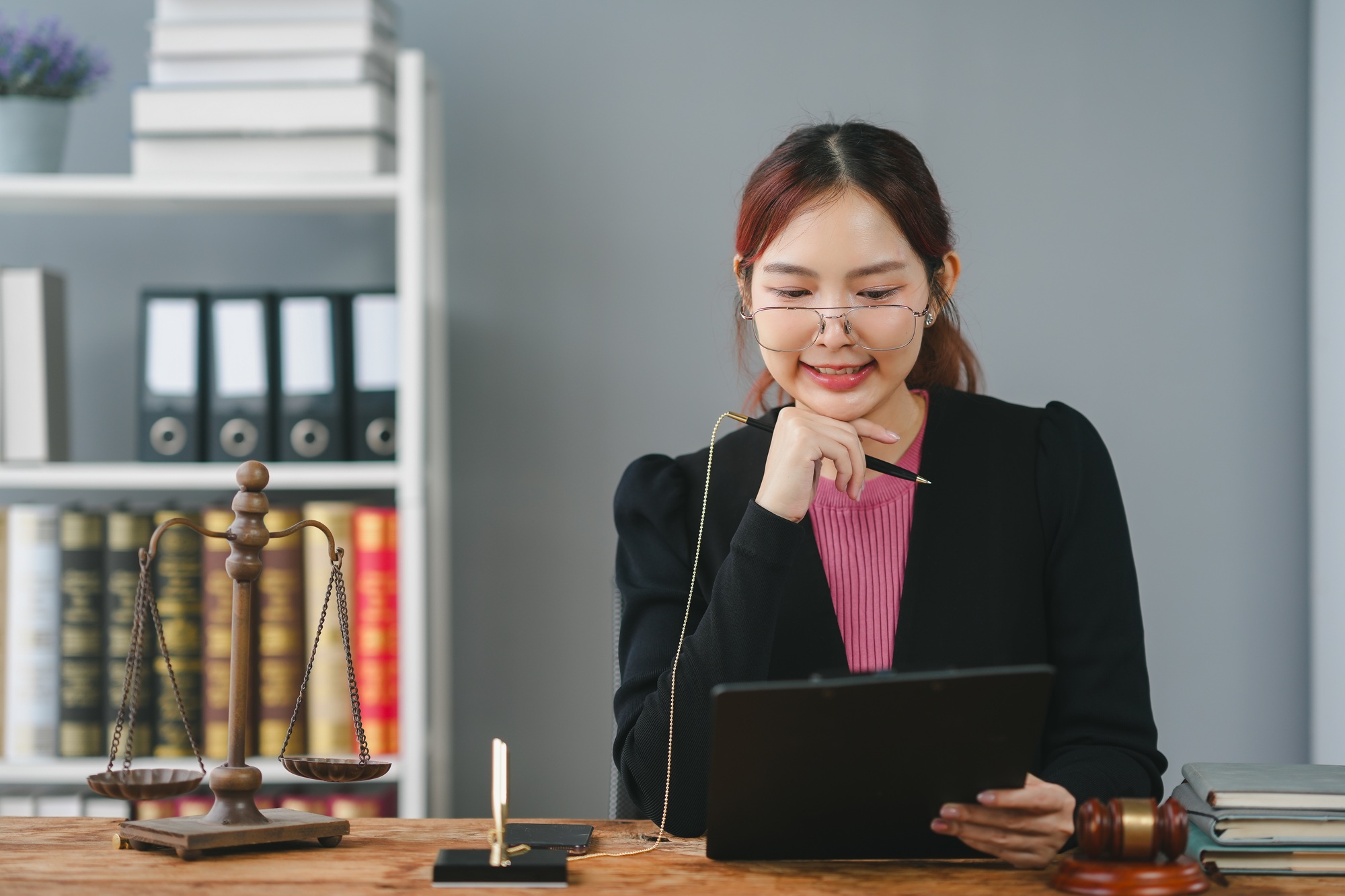A professional woman in a black jacket working at a desk with legal documents