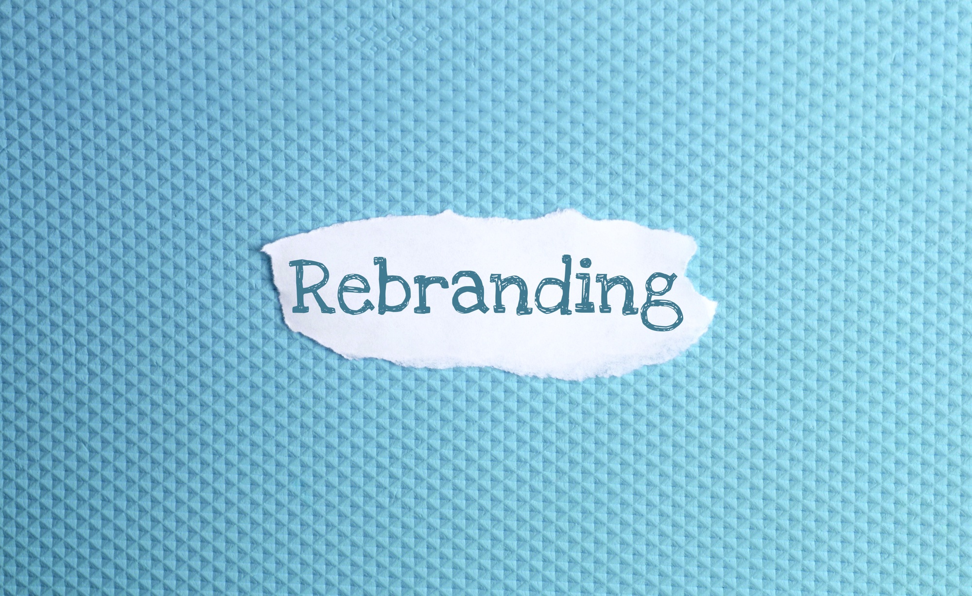 a torn paper written with inscription rebranding on a blue background