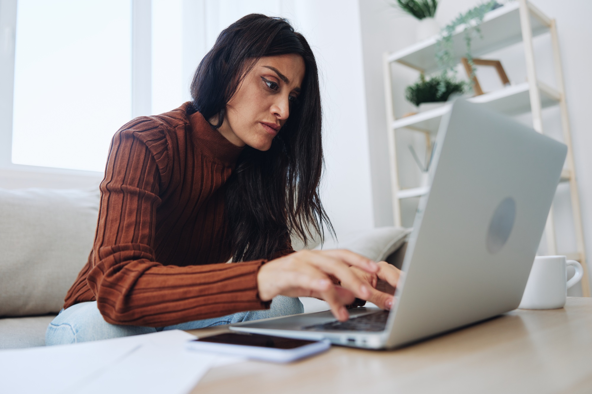A woman does financial calculations and document analysis at home with a laptop, a freelancer works