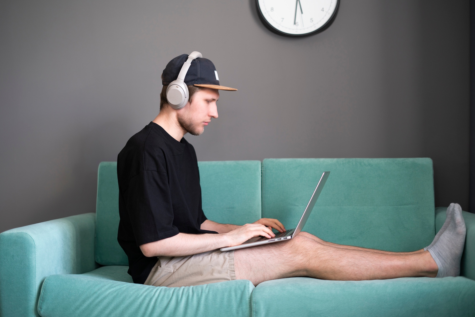 a young man working at home on the couch with laptop, online employee