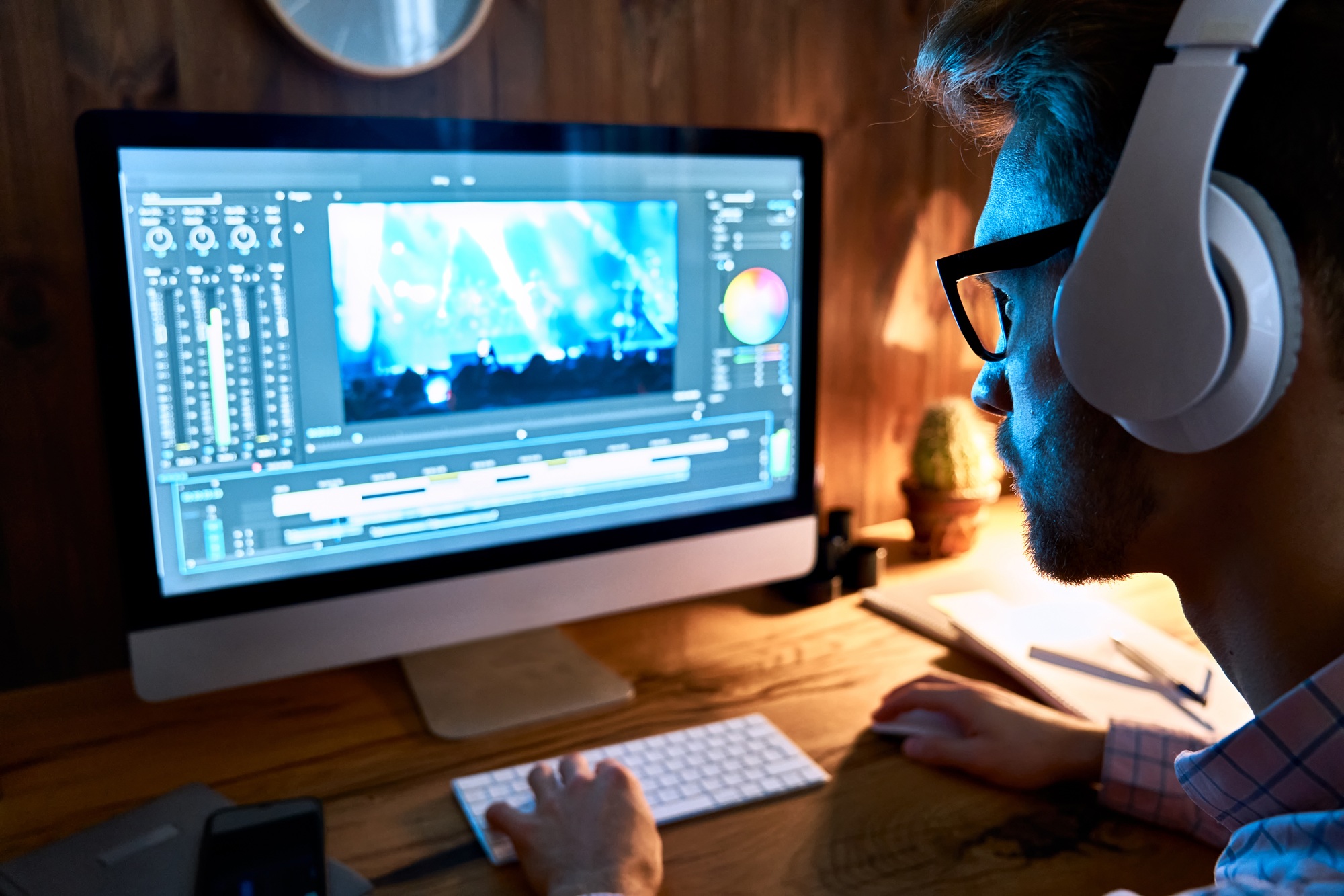 Male videographer editor using pc computer editing footage at home office.