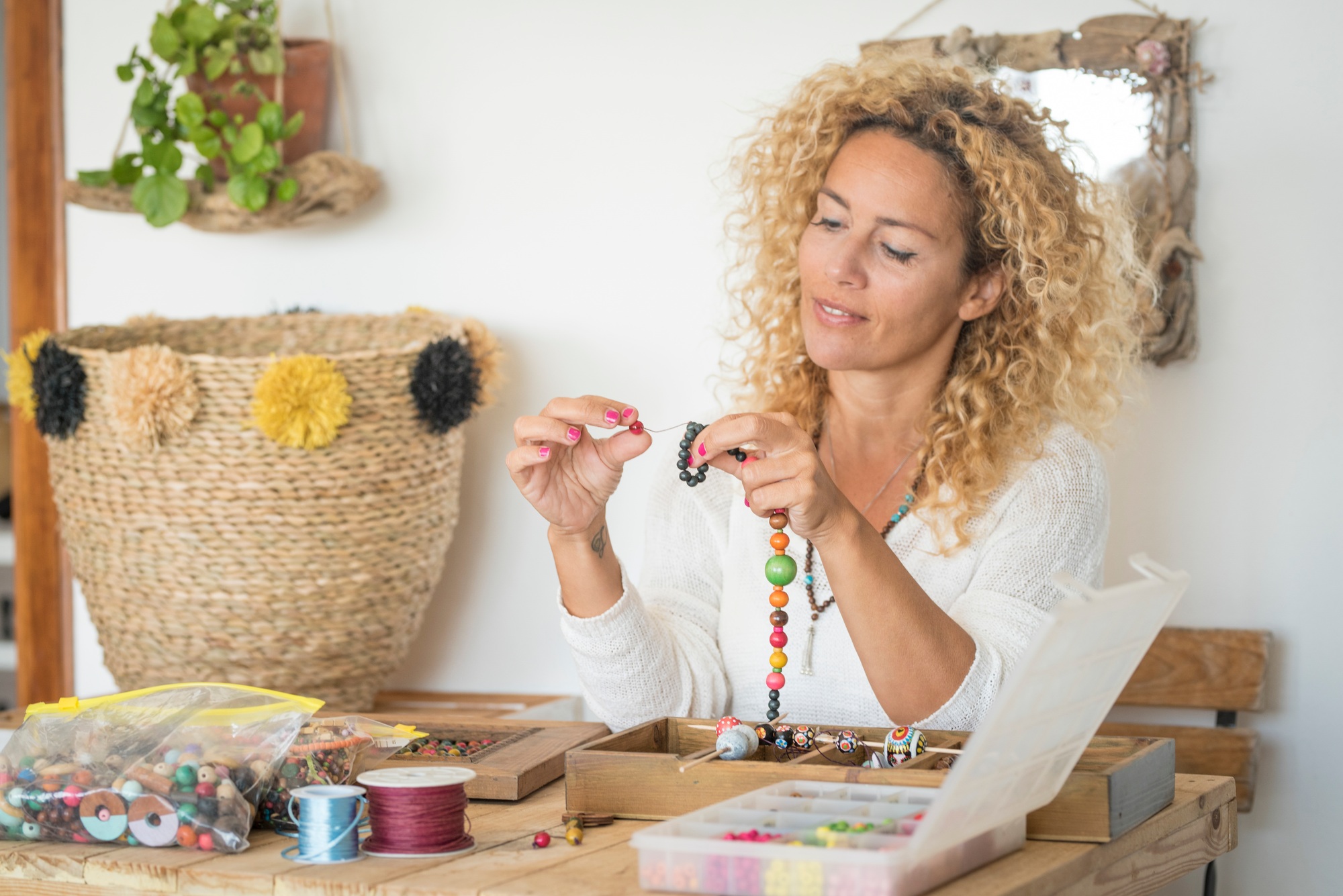 Adult woman doing hand made creations jewelry at home with colorful beads and cords
