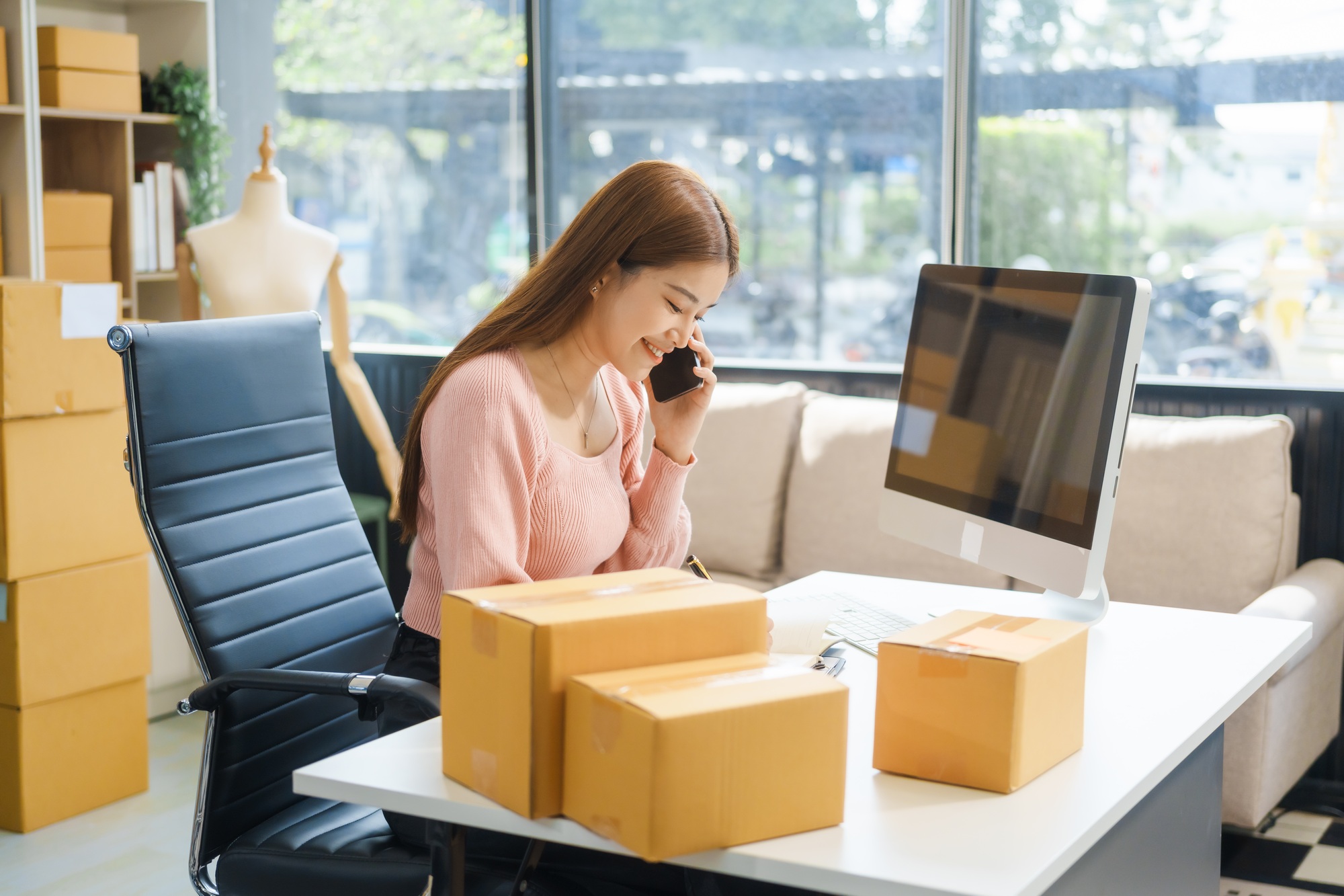 An Asian businesswoman sits at her desk, working on online sales e-commerce marketing strategies