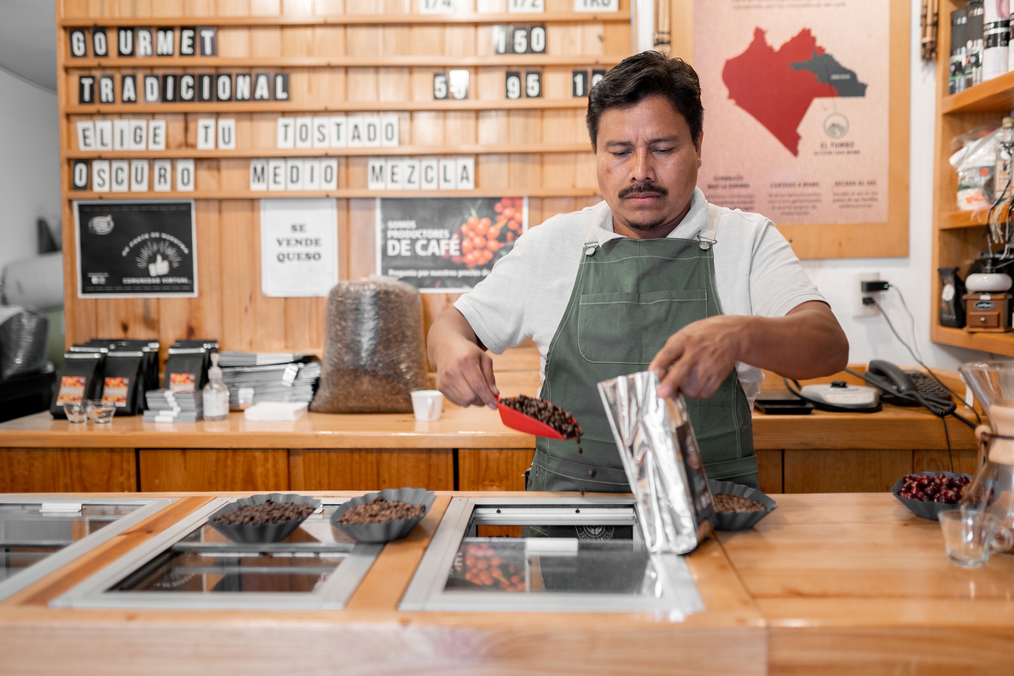 An Hispanic barista is filling a bag with coffee beans for a sell