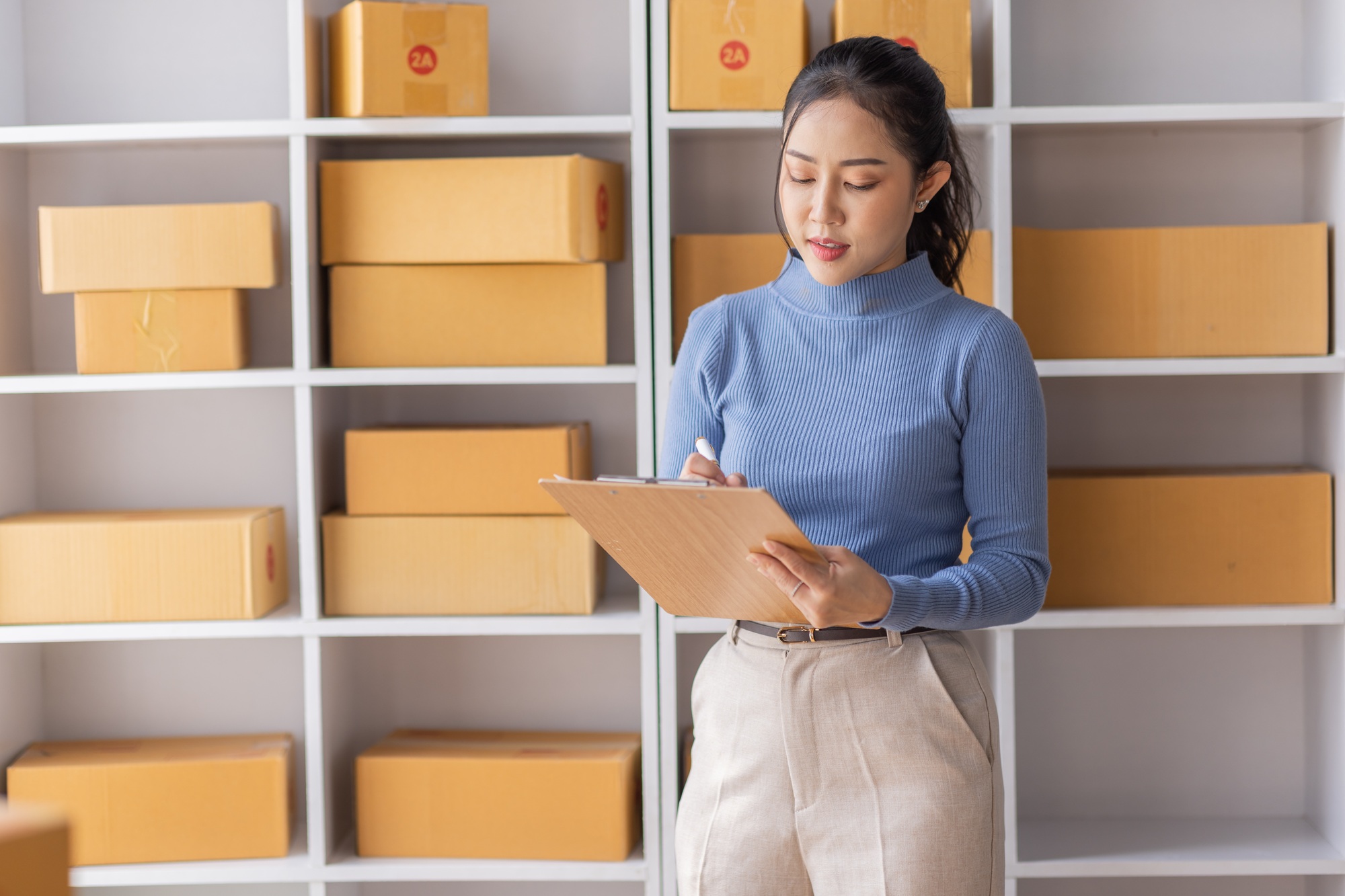 Asian Female entrepreneur starting a small business for SME online sales working with parcel boxes a