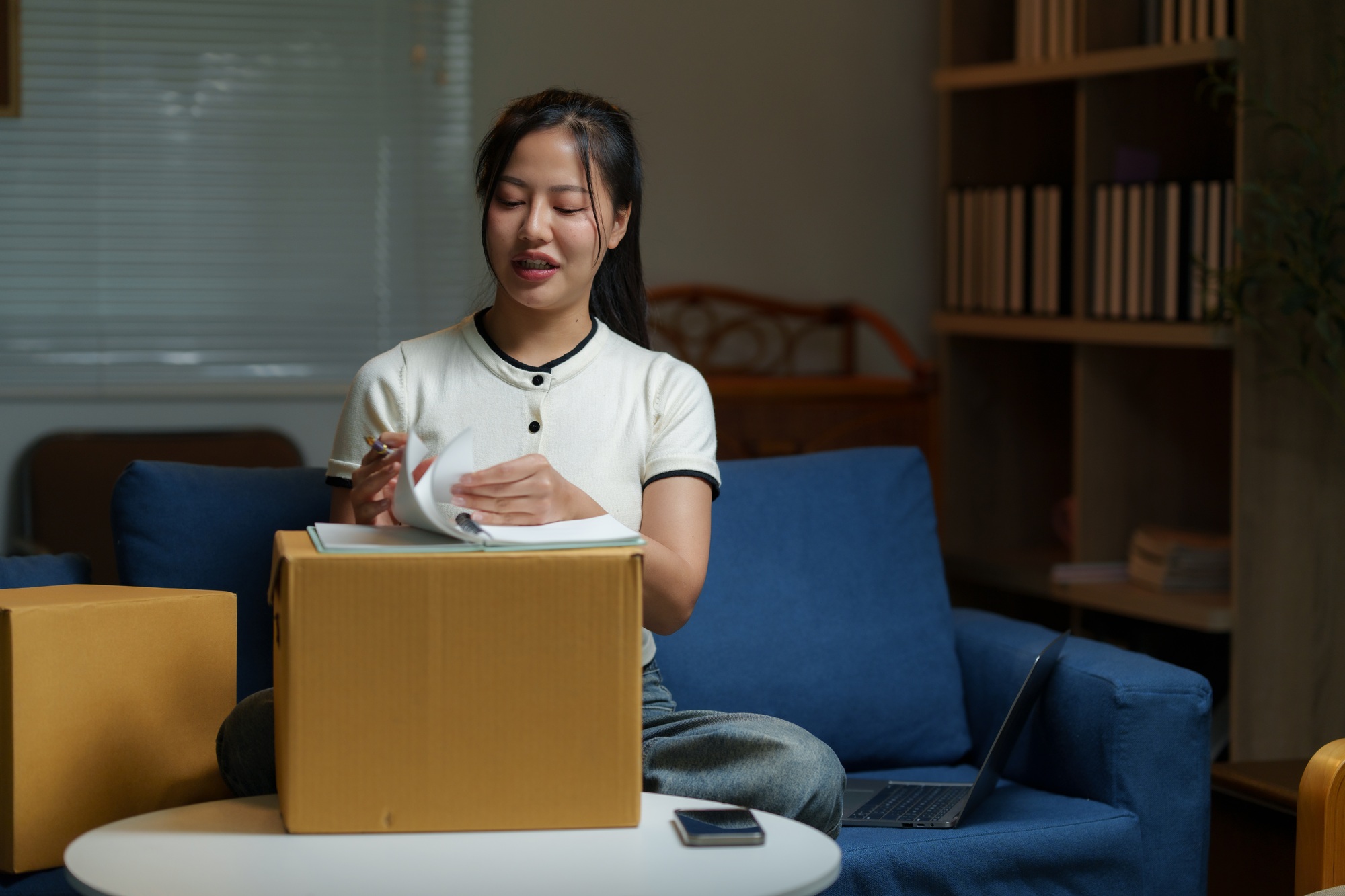 Asian woman managing inventory and preparing packages for shipping at home