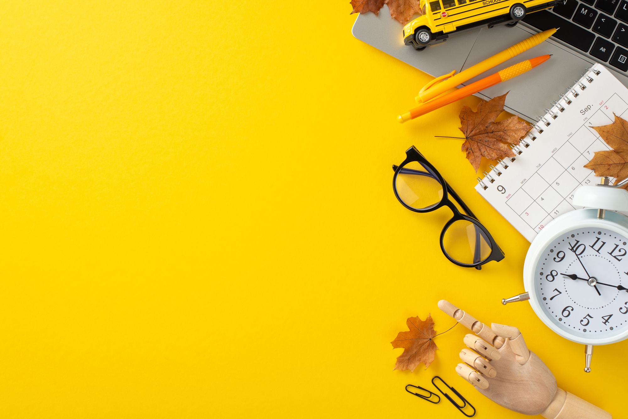Back-to-school essentials: Mannequin hand pointing at variety of supplies, including calendar, clock