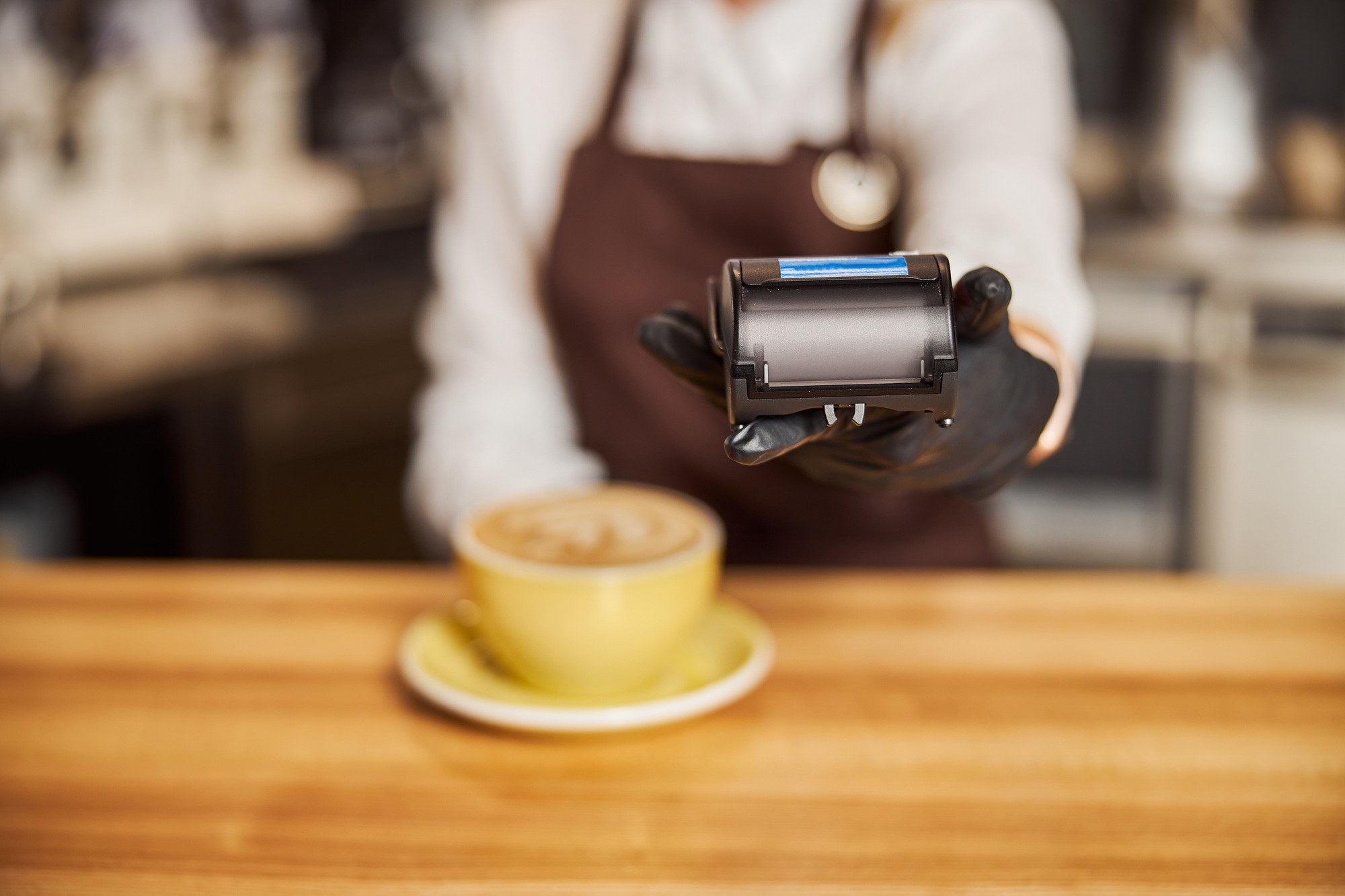 Barista standing near bar counter pay bill using cell application and pos machine